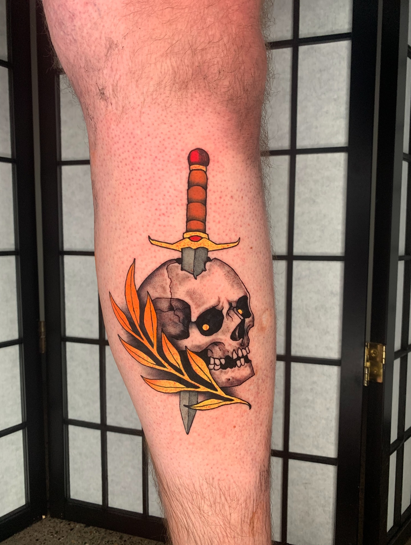 Skull with sword and leaf American traditional tattoo on the forearm by Devon