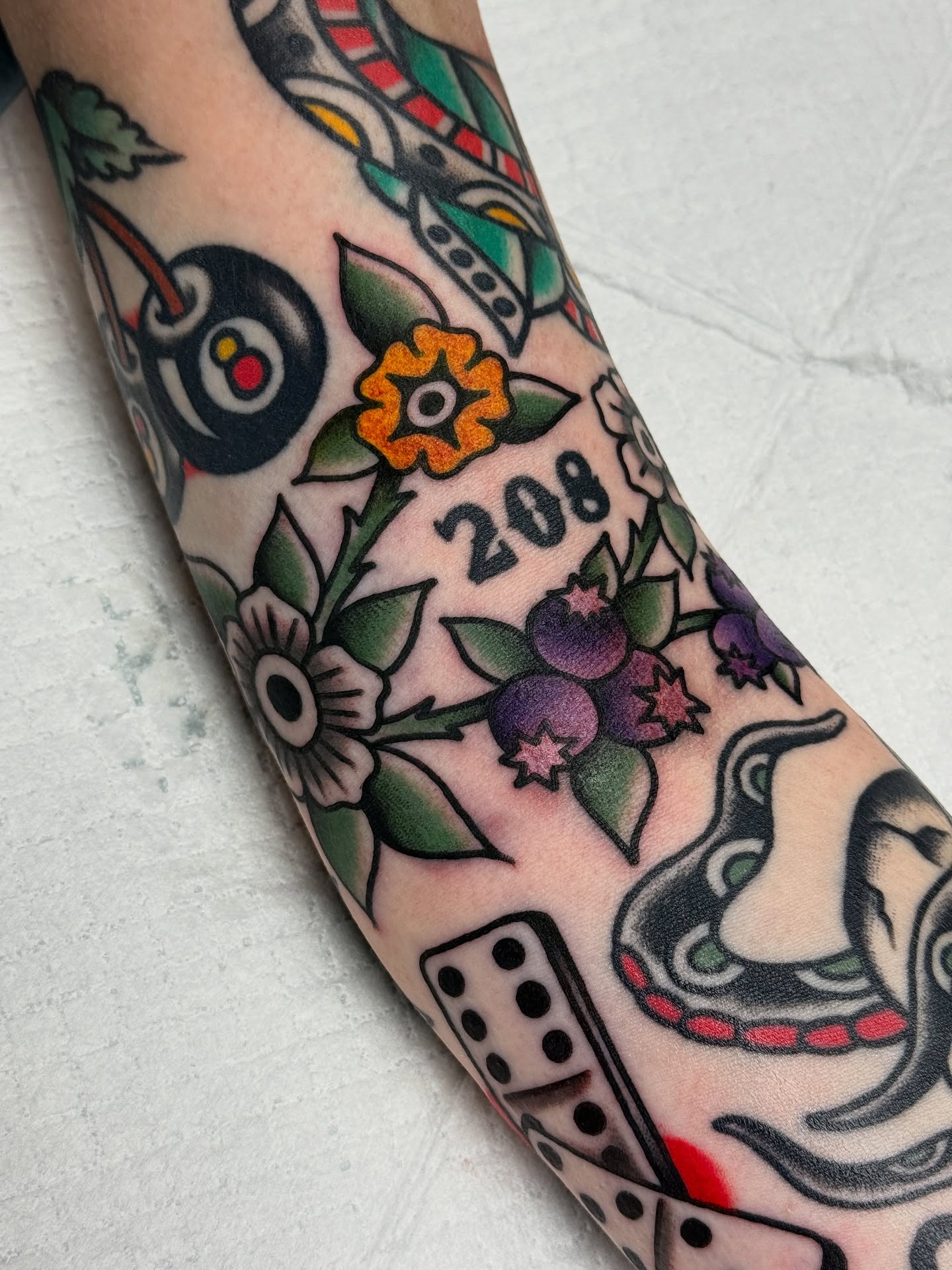 Floral arrangement with dice and numbers American traditional tattoo on the forearm by Jordan Allen