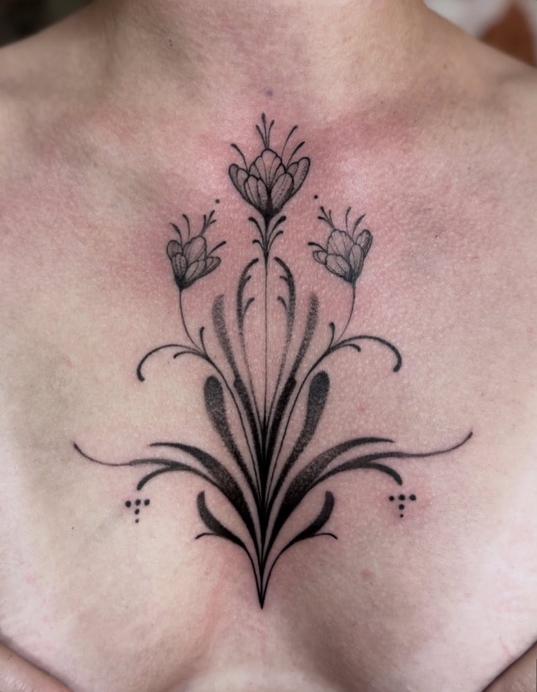 Floral arrangement black and grey tattoo on the chest by Claire Litsey