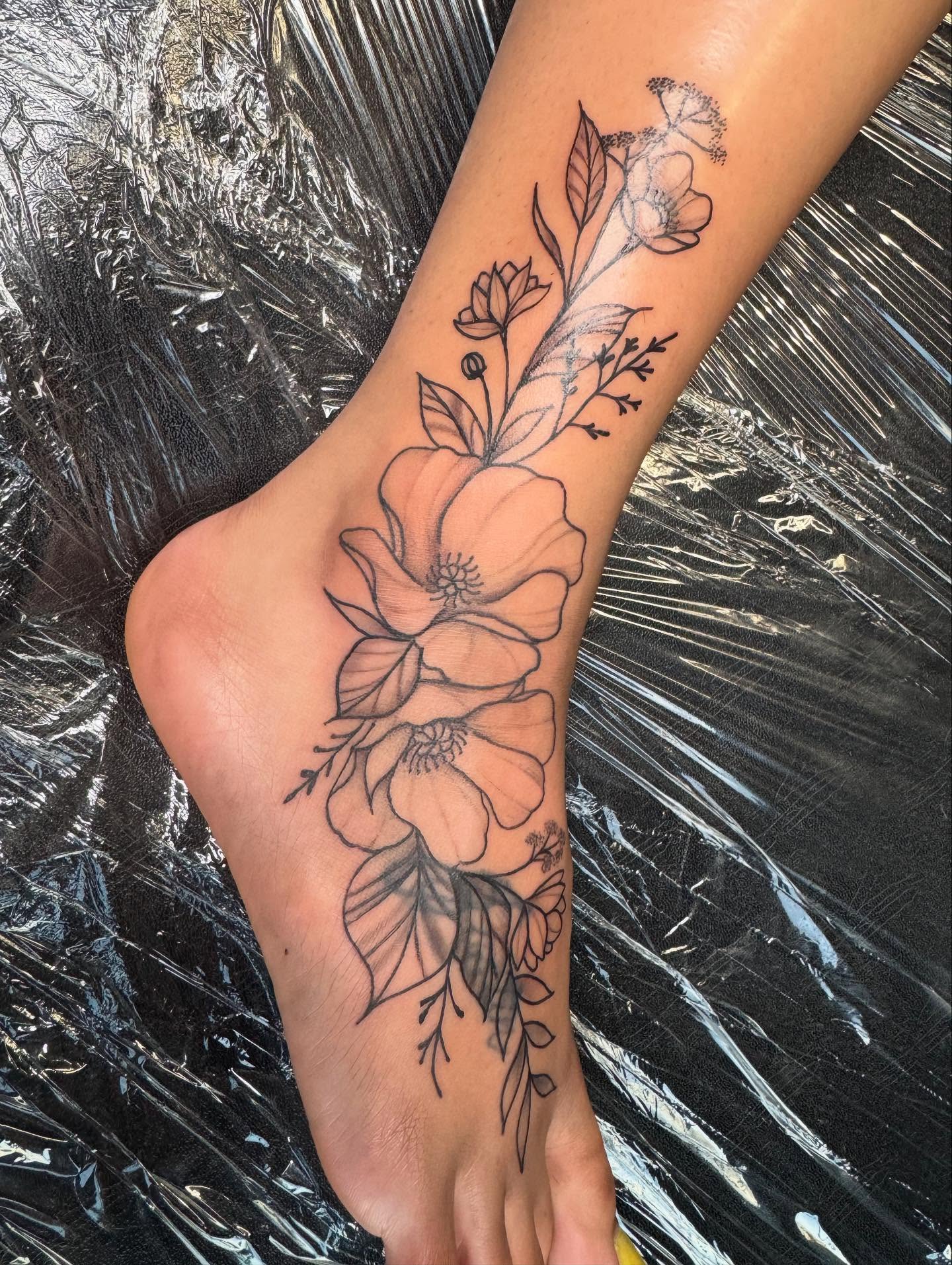 Floral arrangement black and grey tattoo on the foot by Mickey