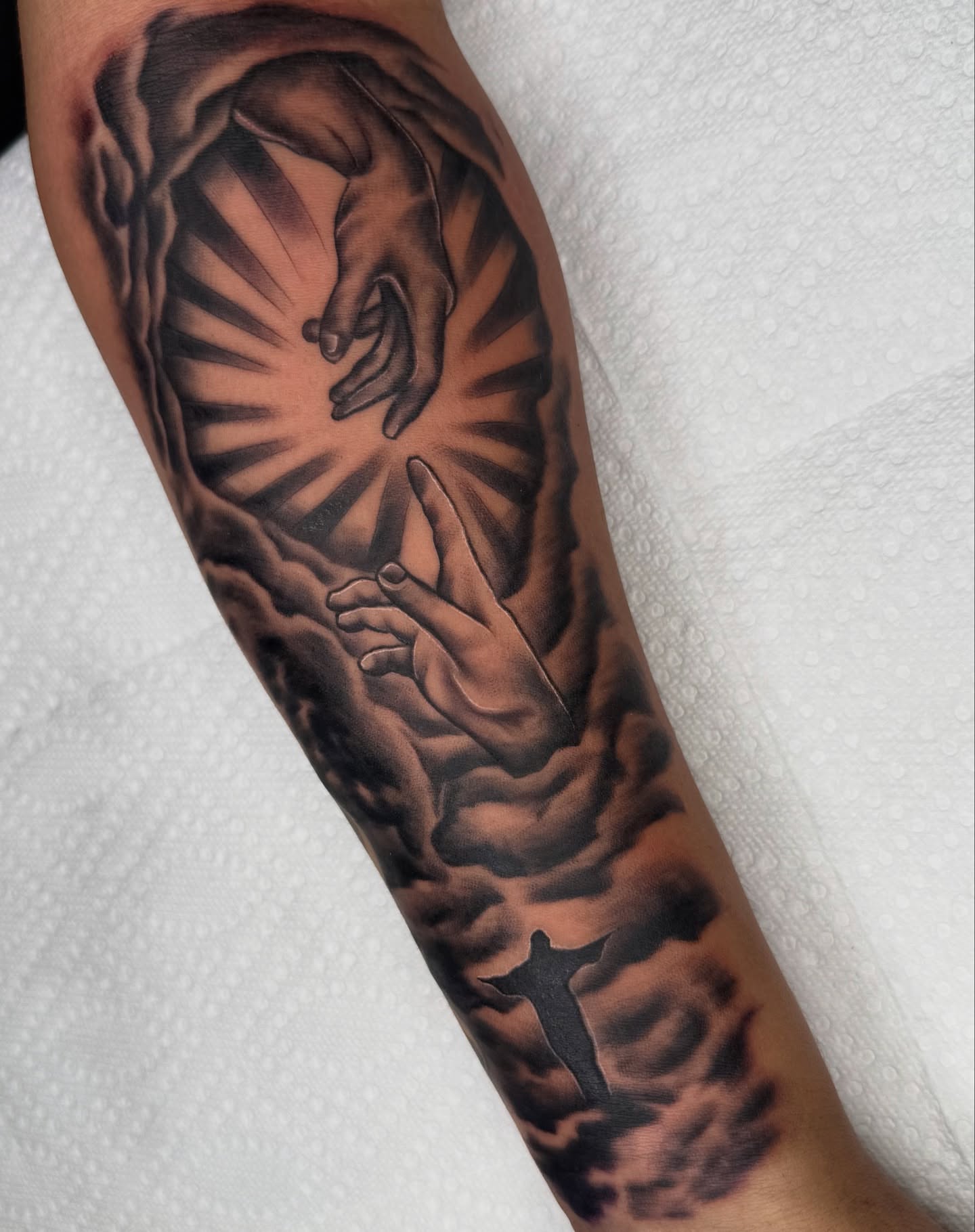 Hands reaching through clouds realism tattoo on the forearm by Elijah East