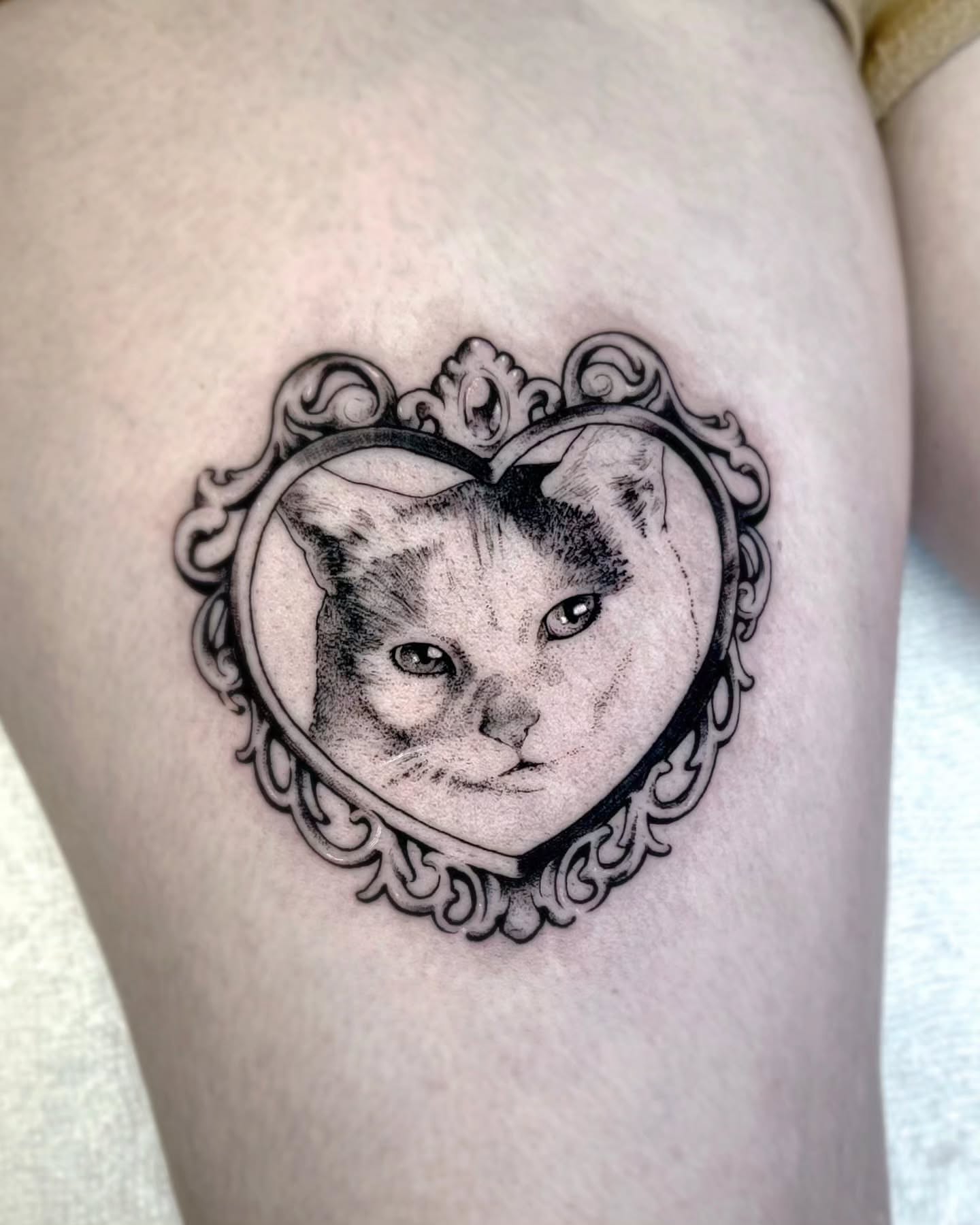 Cat in heart frame realism tattoo on the thigh by Luca