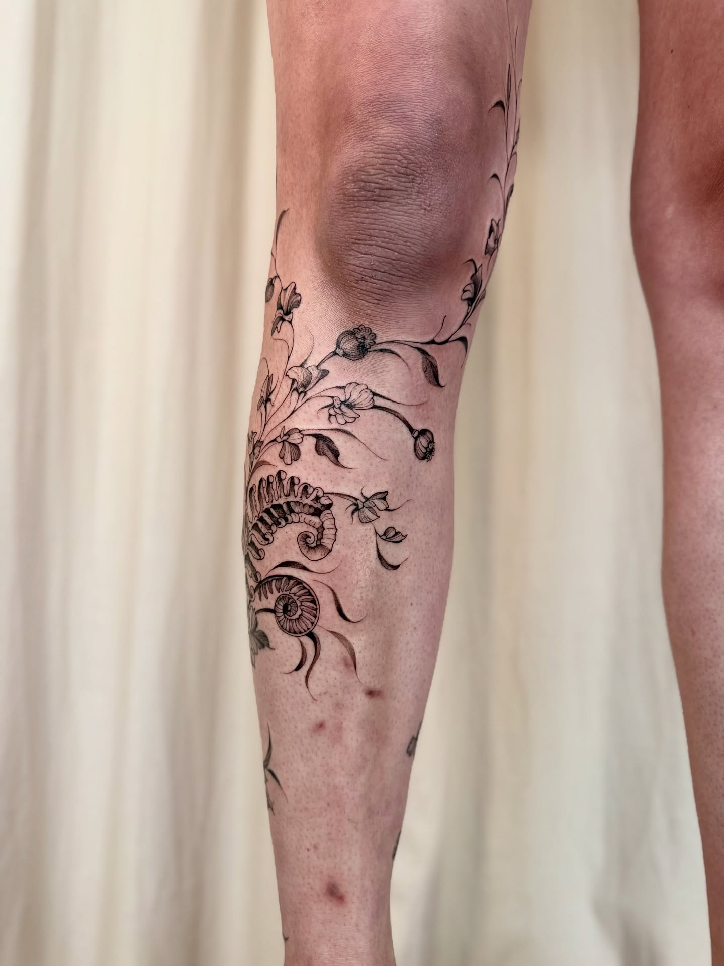 Seashell and floral black and grey tattoo on the calf by Dung Ngo