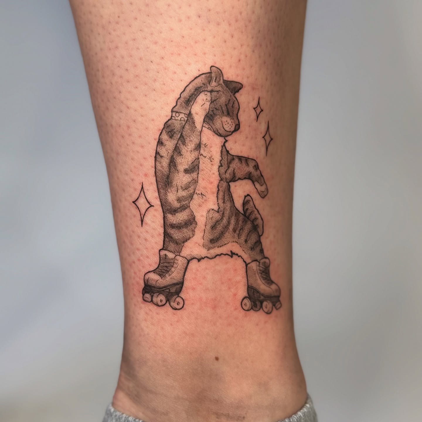 Cat on roller skates black and grey tattoo on the calf by bre