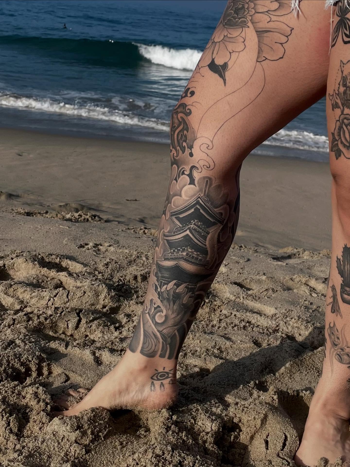 Wave and temple black and grey tattoo on the calf by Daniel Gutierrez