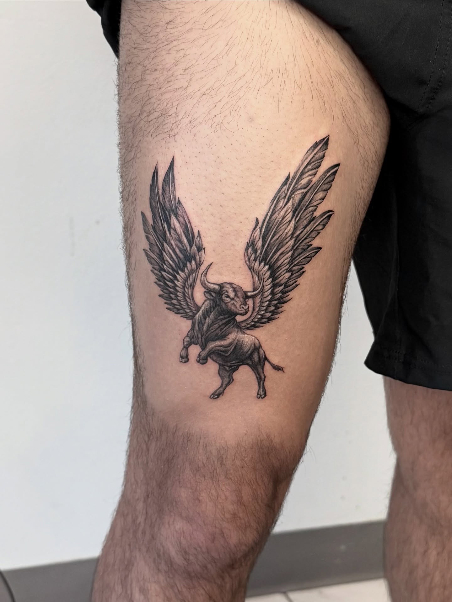 Winged bull black and grey tattoo on the thigh by Miro Ink Tattoo
