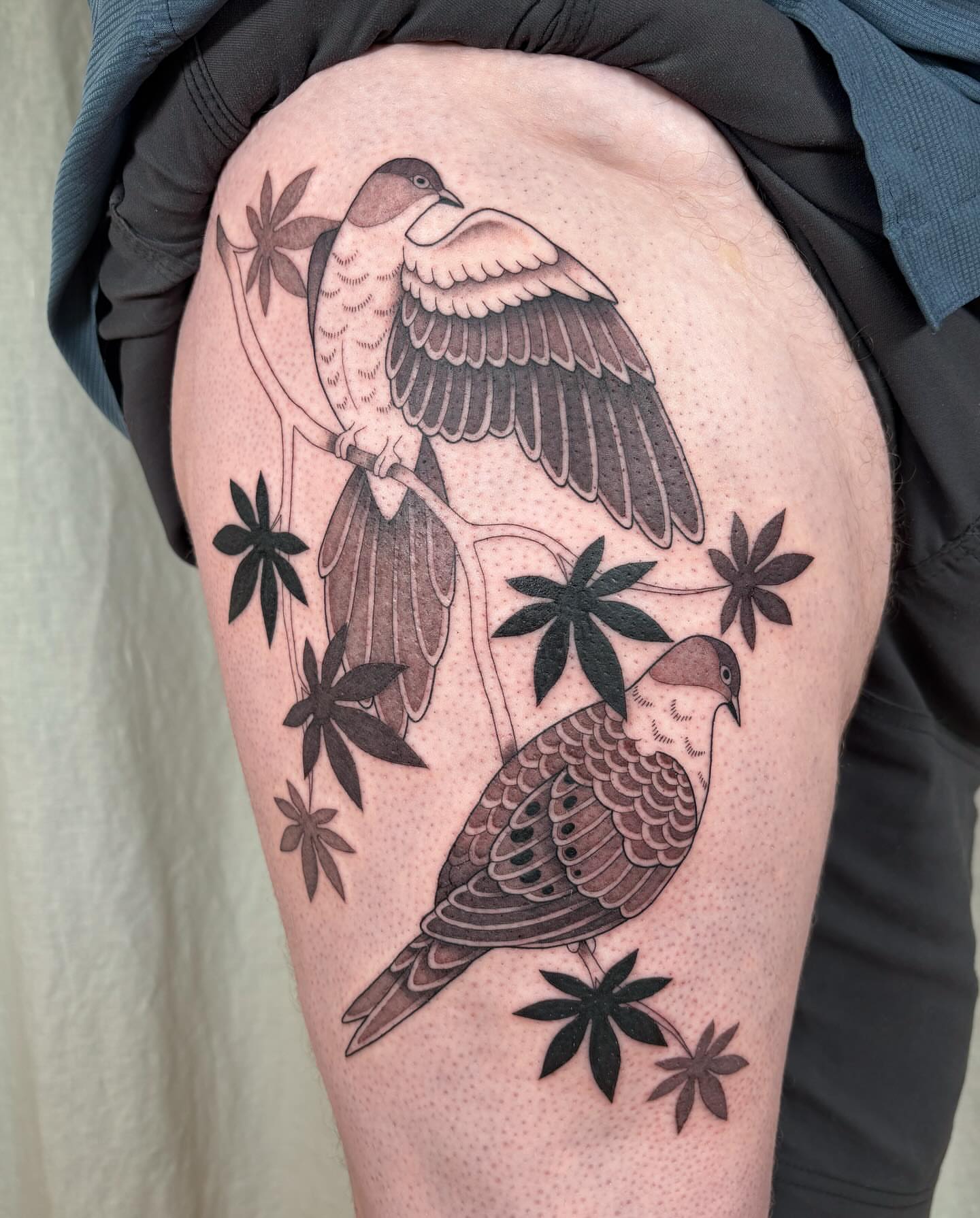 Doves and cannabis leaves black and grey tattoo on the thigh by Anna Sage