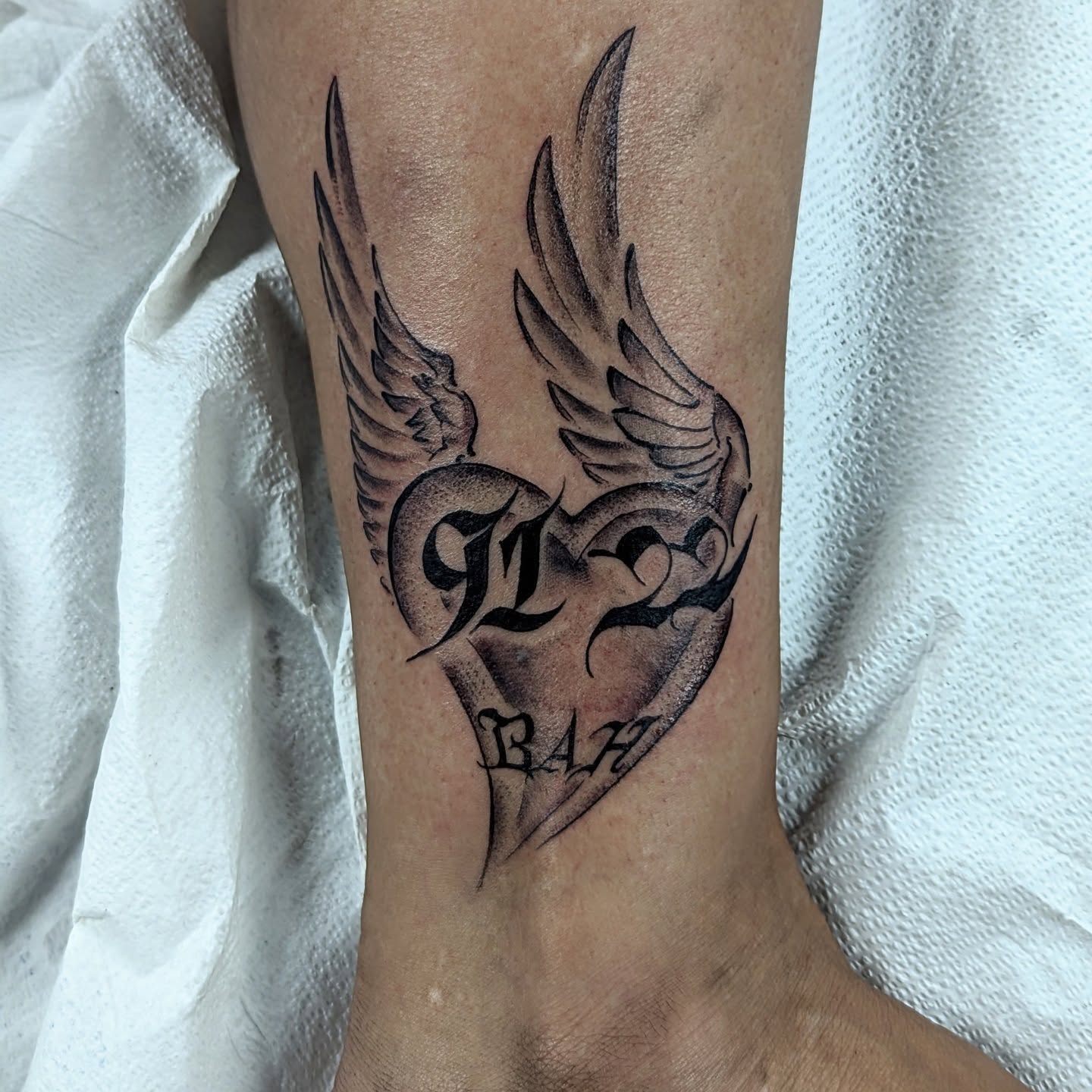 Heart with wings black and grey tattoo on the forearm by DONEL 📍Denver