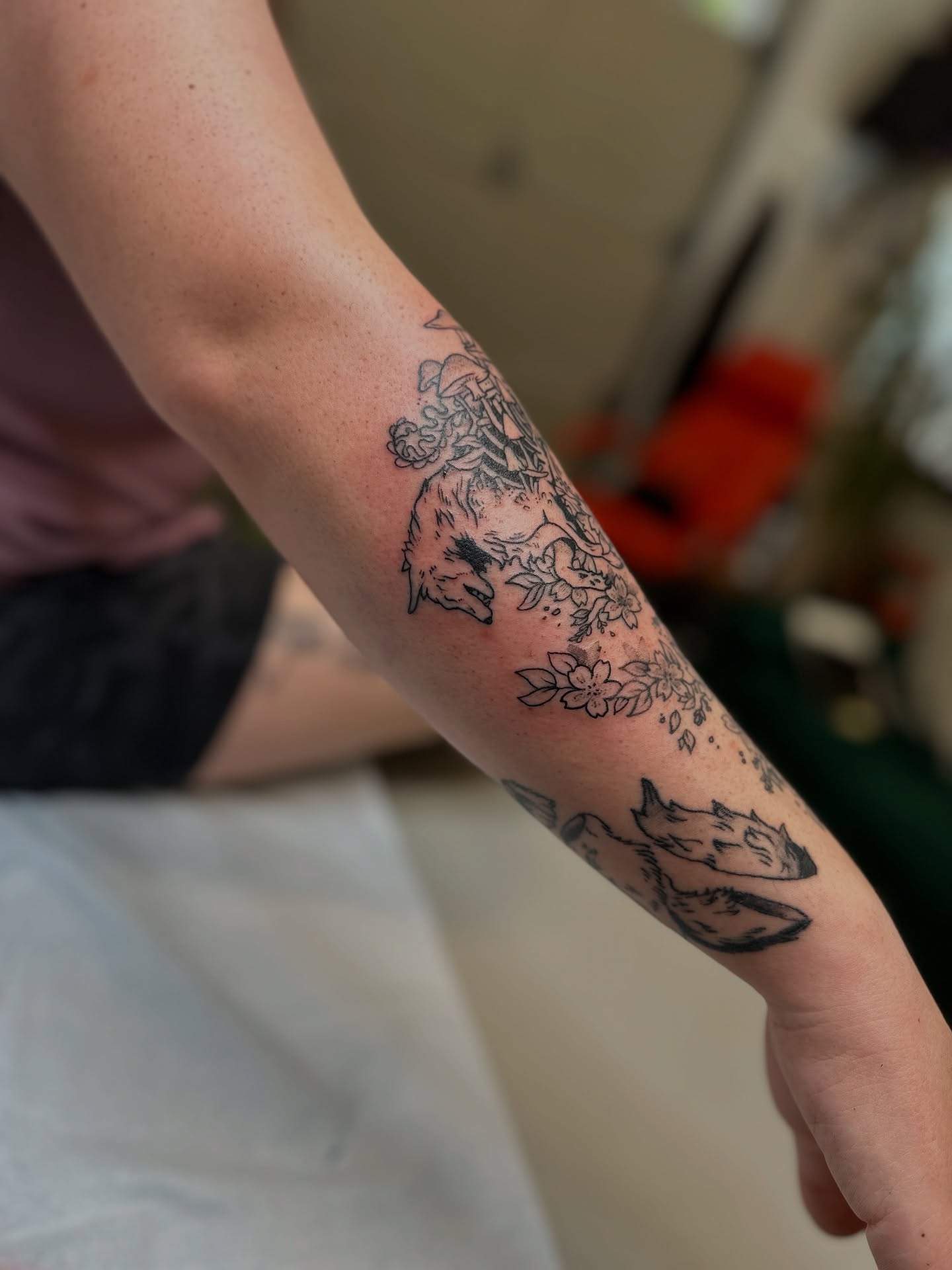 Foxes and flowers black and grey tattoo on the forearm by Emma Berger