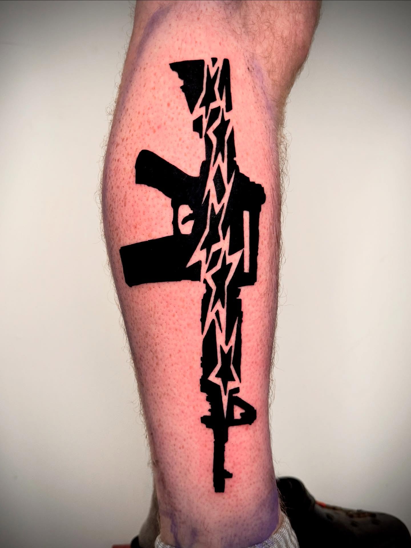 Machine gun black and grey tattoo on the leg by 𝔠𝔲𝔯𝔱𝔦𝔰 ~ tattoo artist
