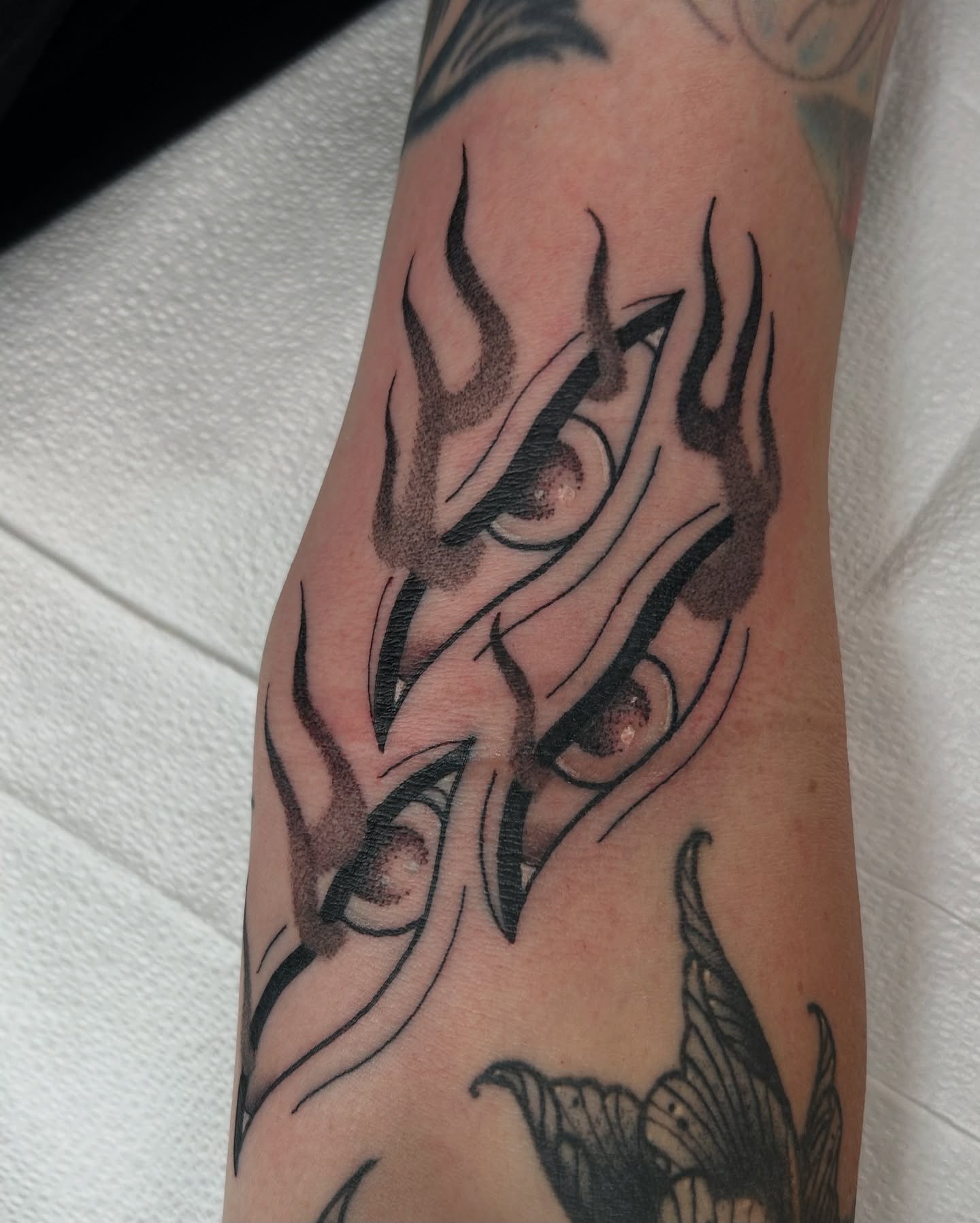 Flame black and grey tattoo on the forearm by Noah Crow