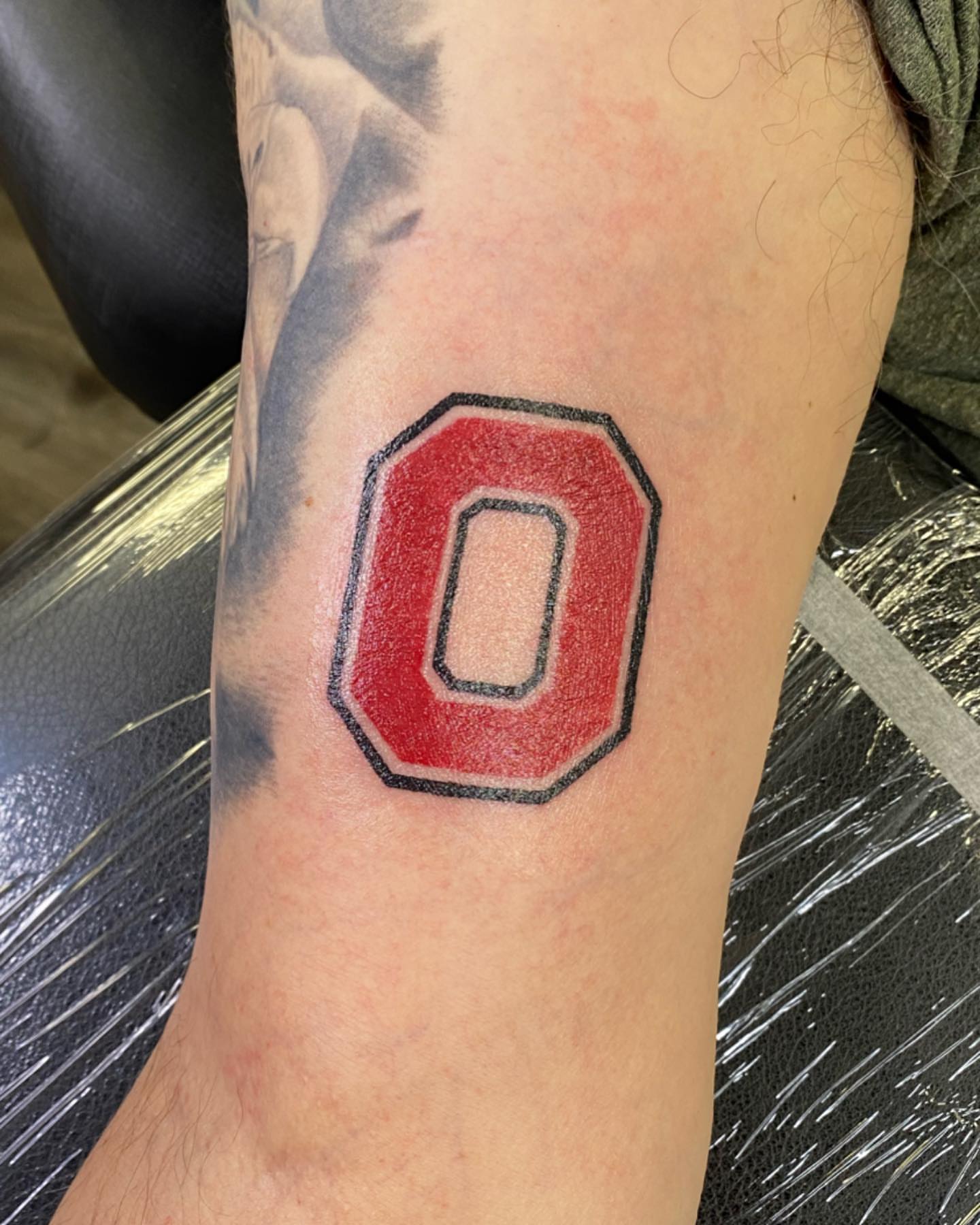 Red letter O American traditional tattoo on the forearm by Spencer Jones Tattoos