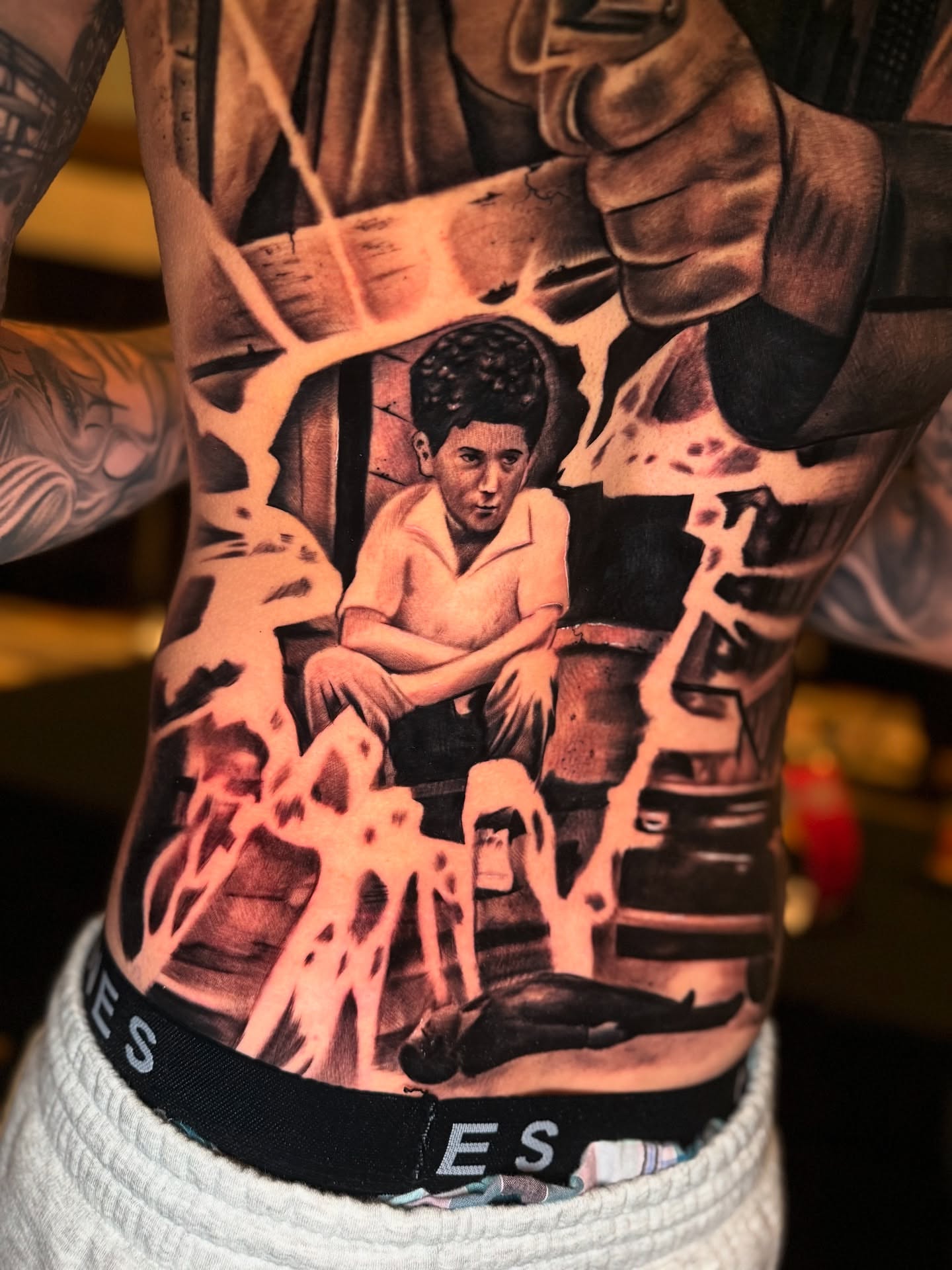 Boy sitting realism tattoo on the torso by Jose Mendoza Torres