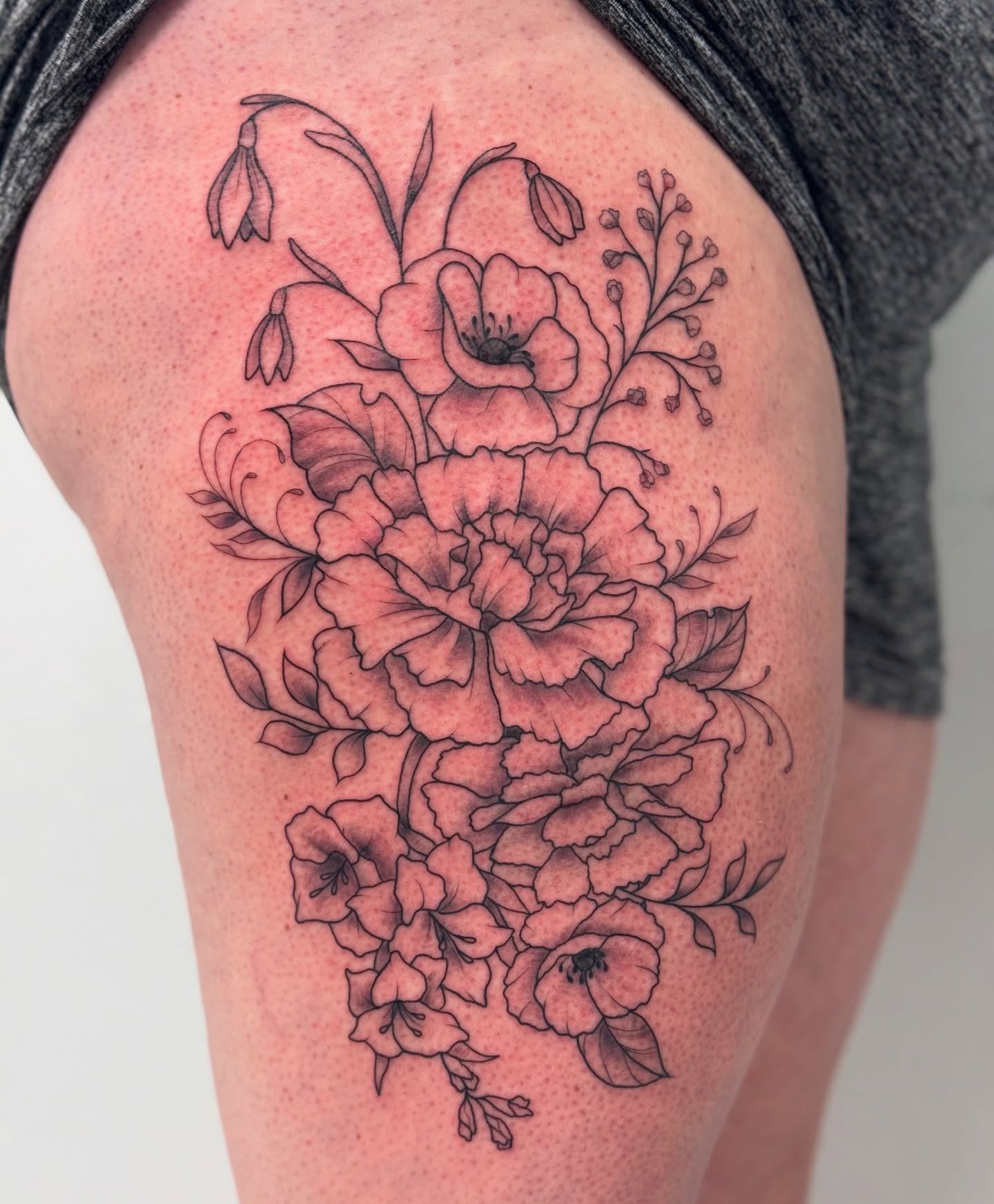 Floral bouquet black and grey tattoo on the thigh by Lacee-Beth Finch