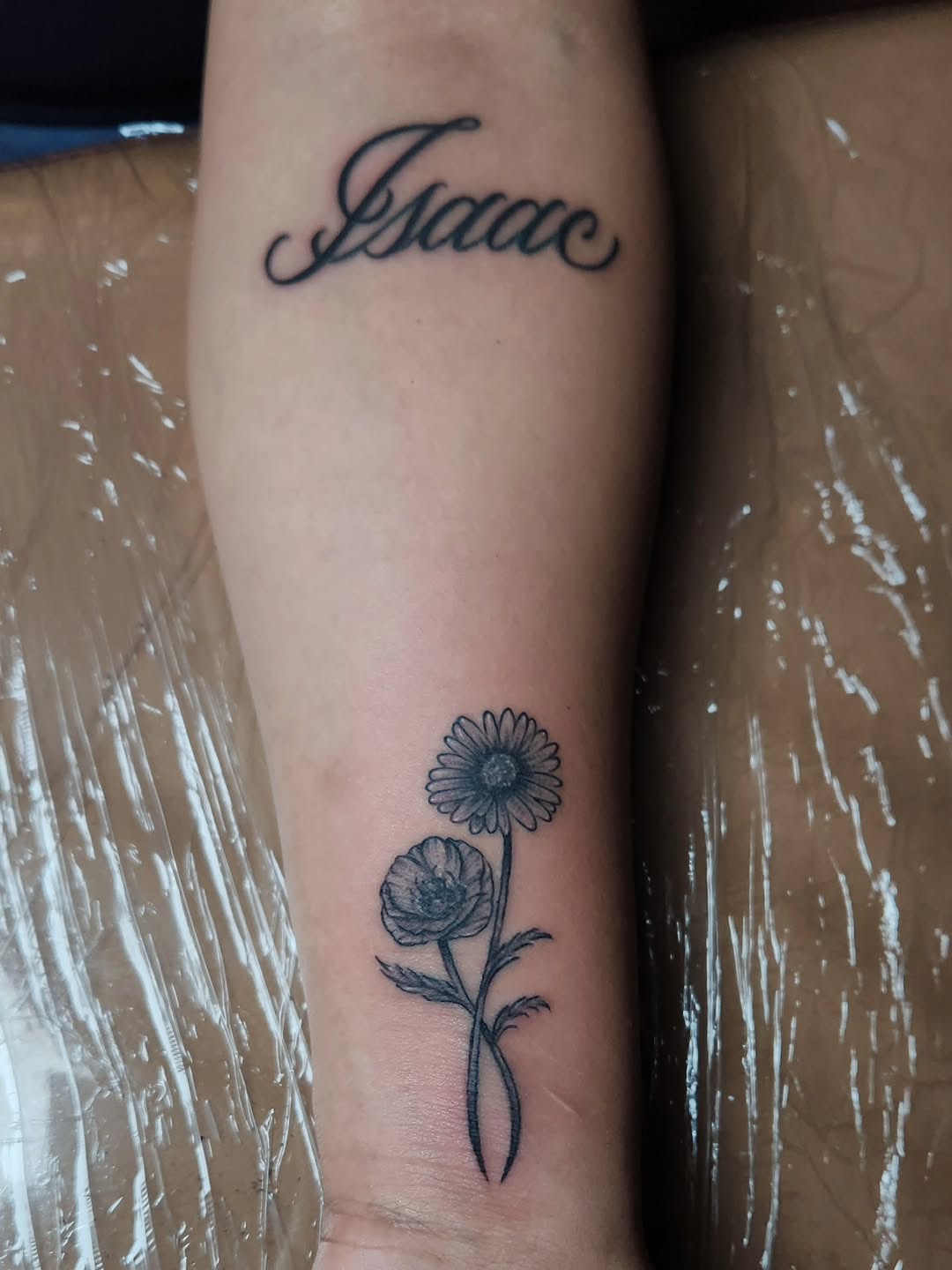 Flower and script black and grey tattoo on the forearm by @youxg_guxxz