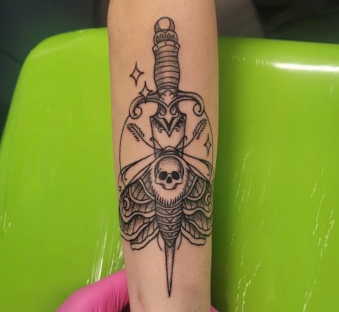 Knife and moth black and grey tattoo on the forearm by Wray Saulsberry
