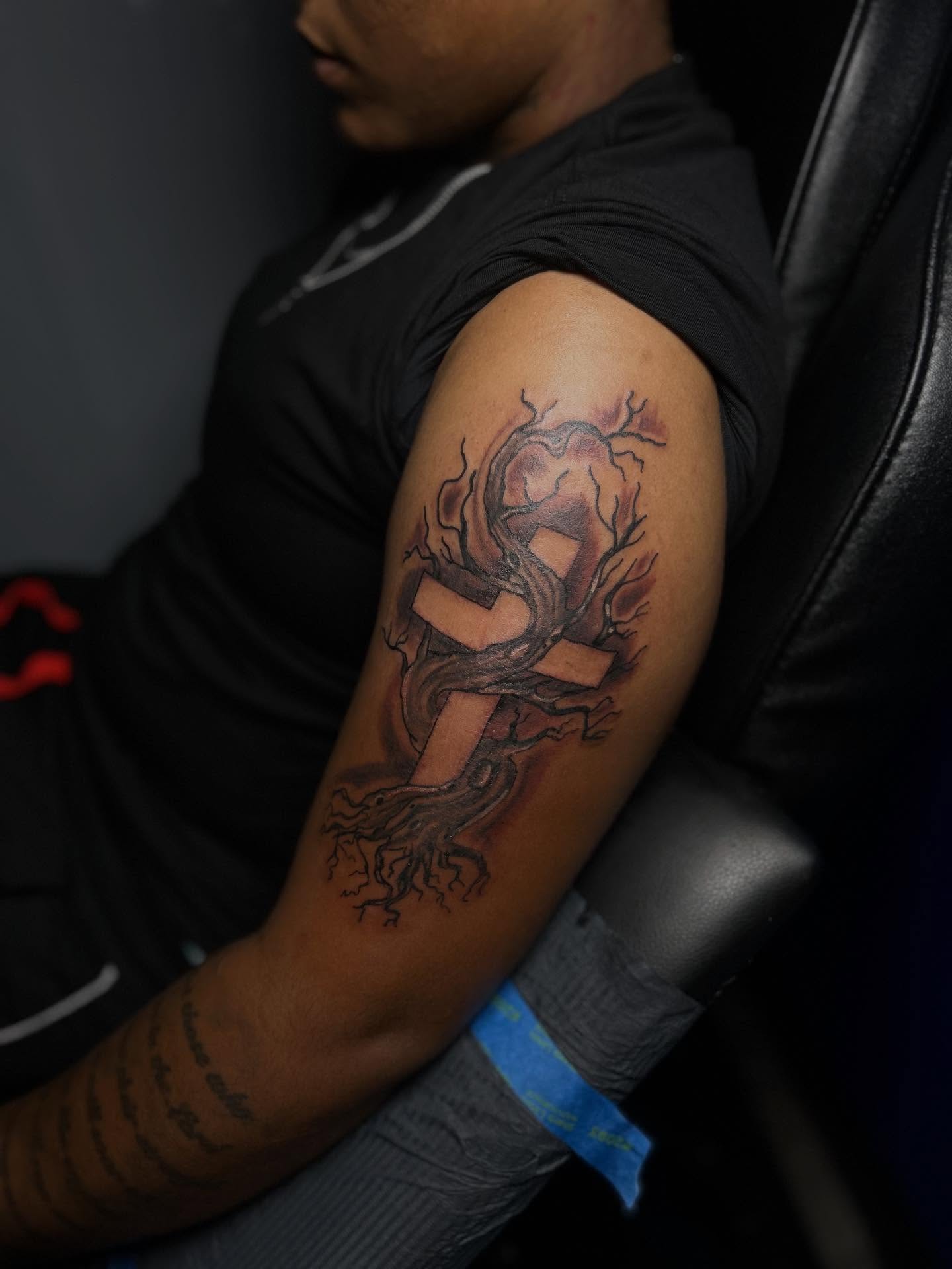 Cross with tree roots black and grey tattoo on the forearm by Rell Washington, Marlow Heights, Maryland
