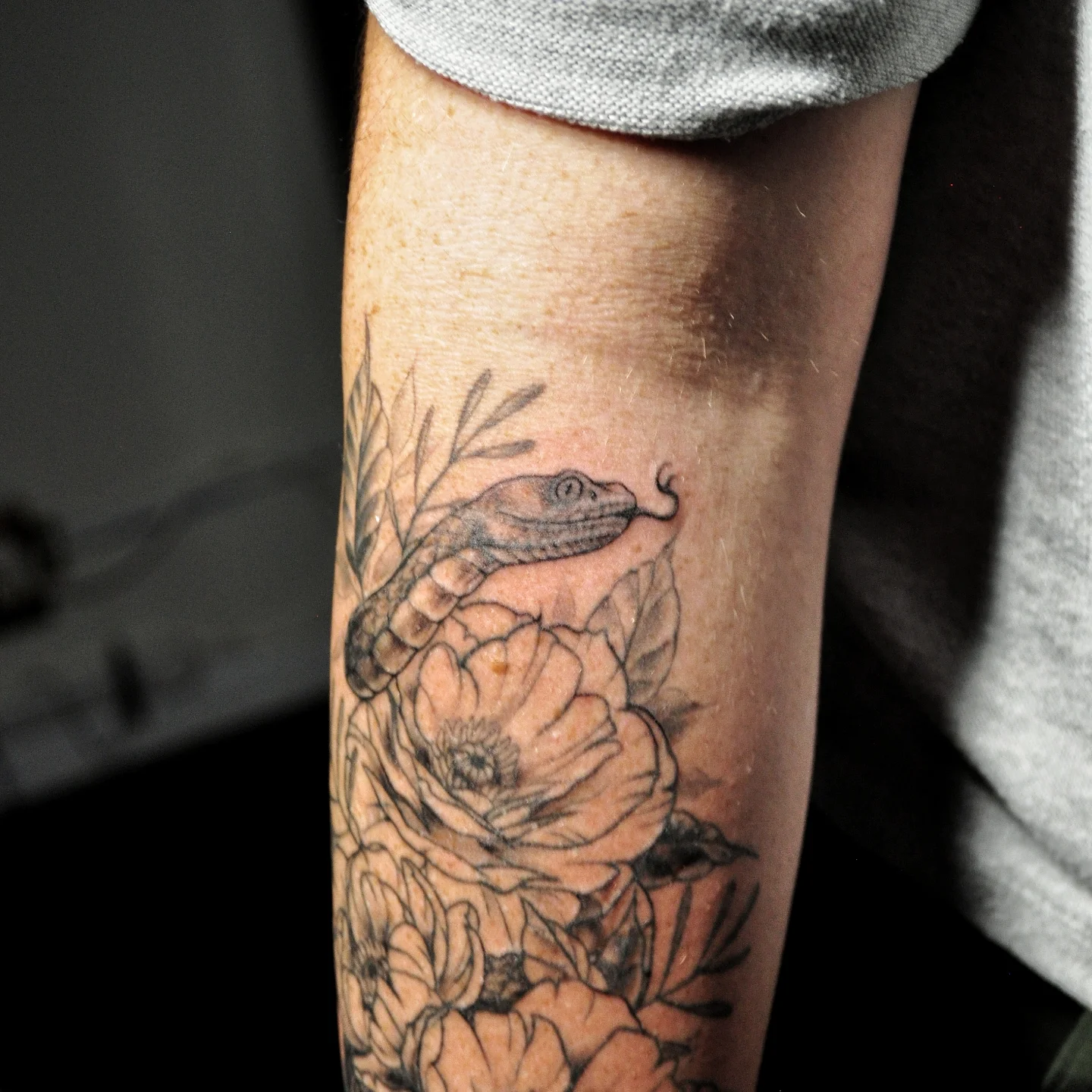 Snake and peony black and grey tattoo on the forearm by Bek Artz