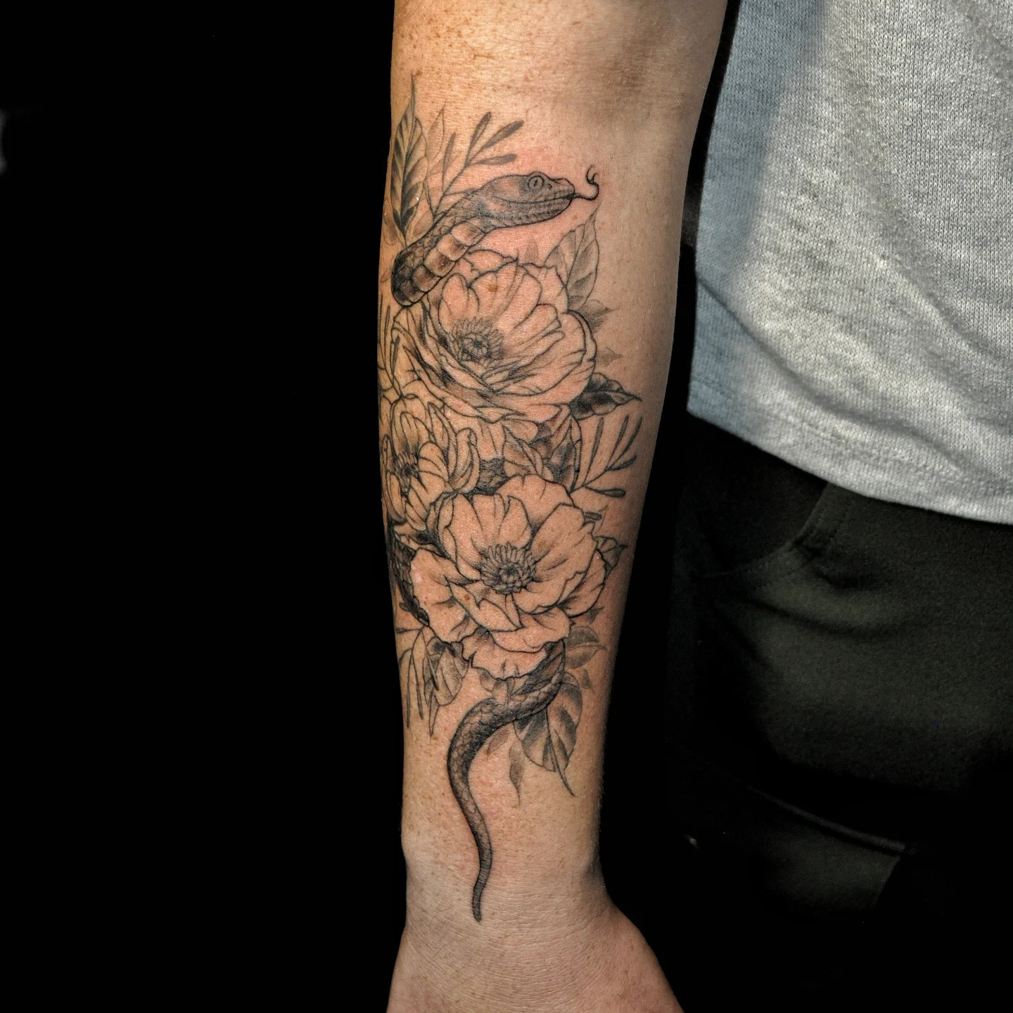 Snake and peony black and grey tattoo on the forearm by Bek Artz