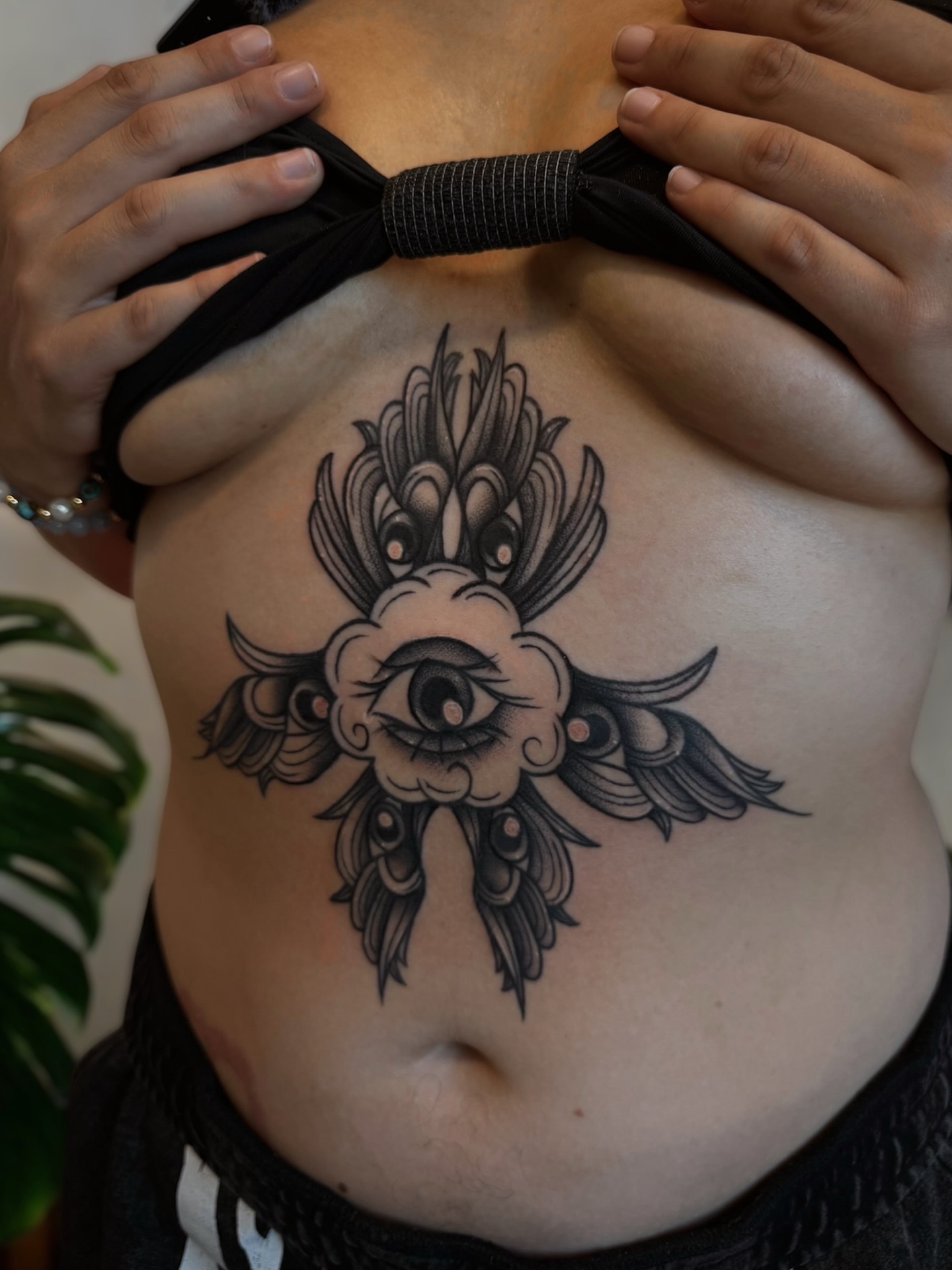Eye with floral wings American traditional tattoo on the ribs by Daphne Love