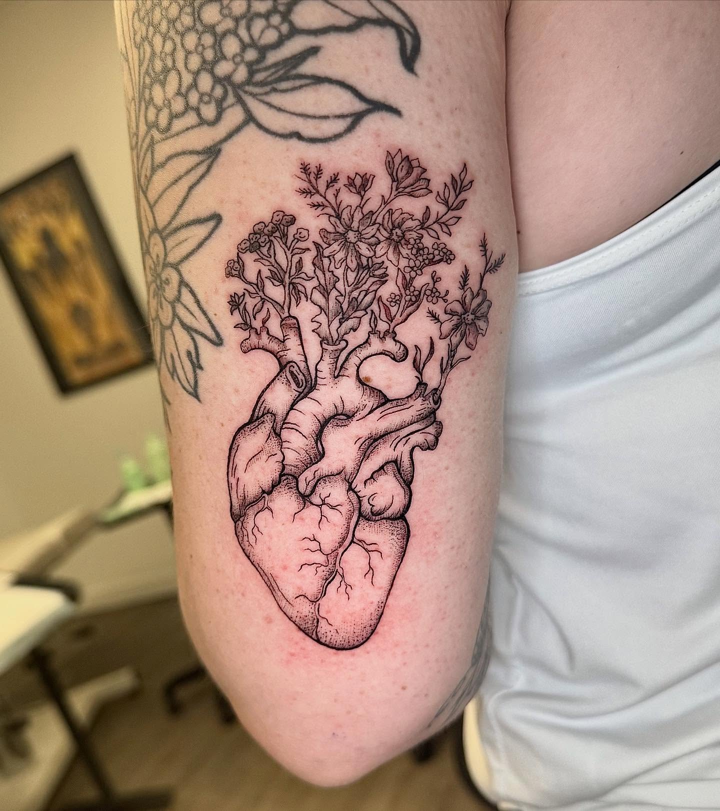 Anatomical heart with floral growth realism tattoo on the forearm by Tyla Pistak, Seattle, Washington