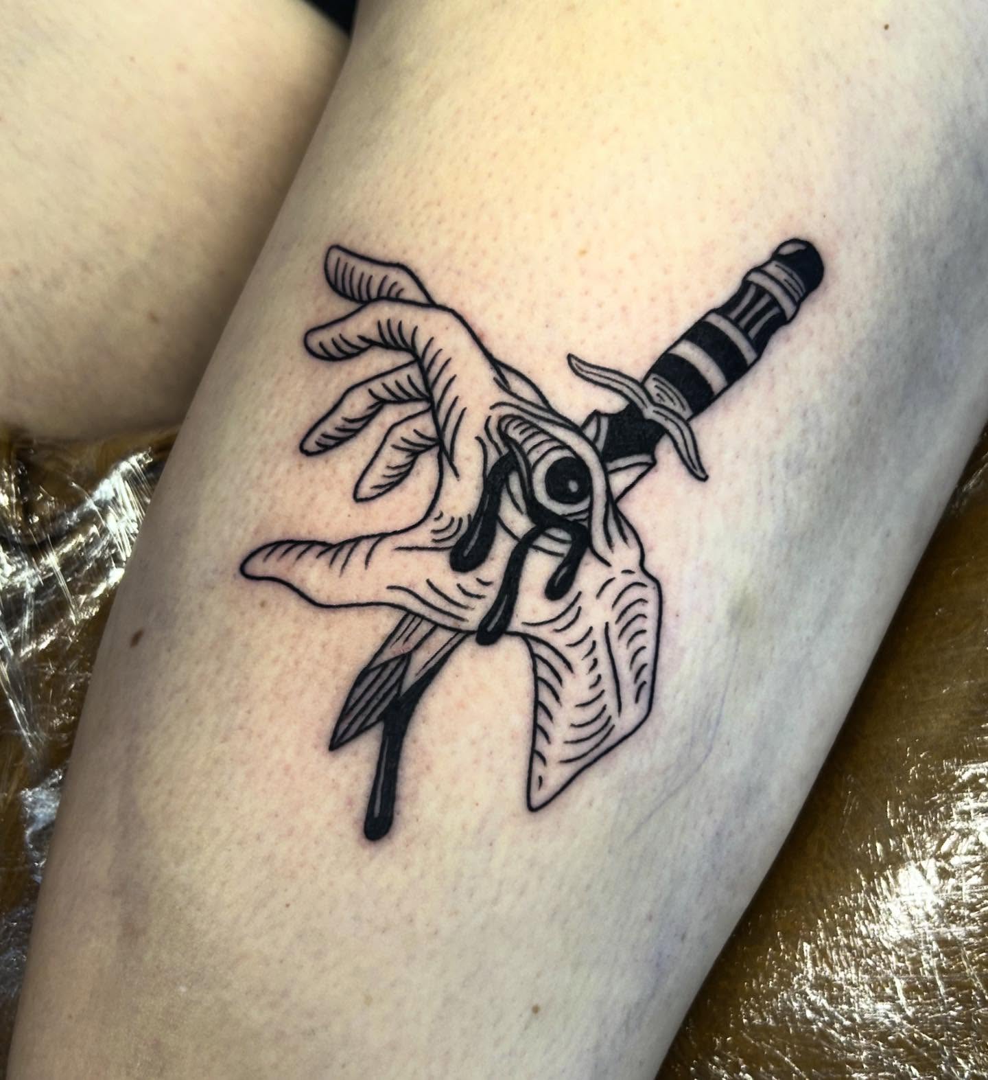 Knife and hand black and grey tattoo on the forearm by Nikki Power
