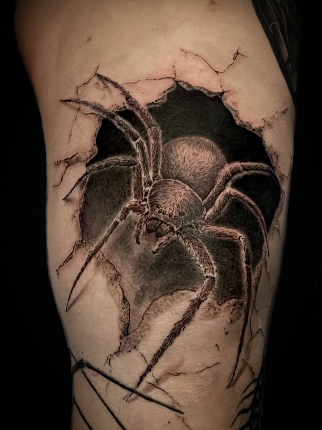 Spider breaking through skin blackwork tattoo on the forearm by Charlie