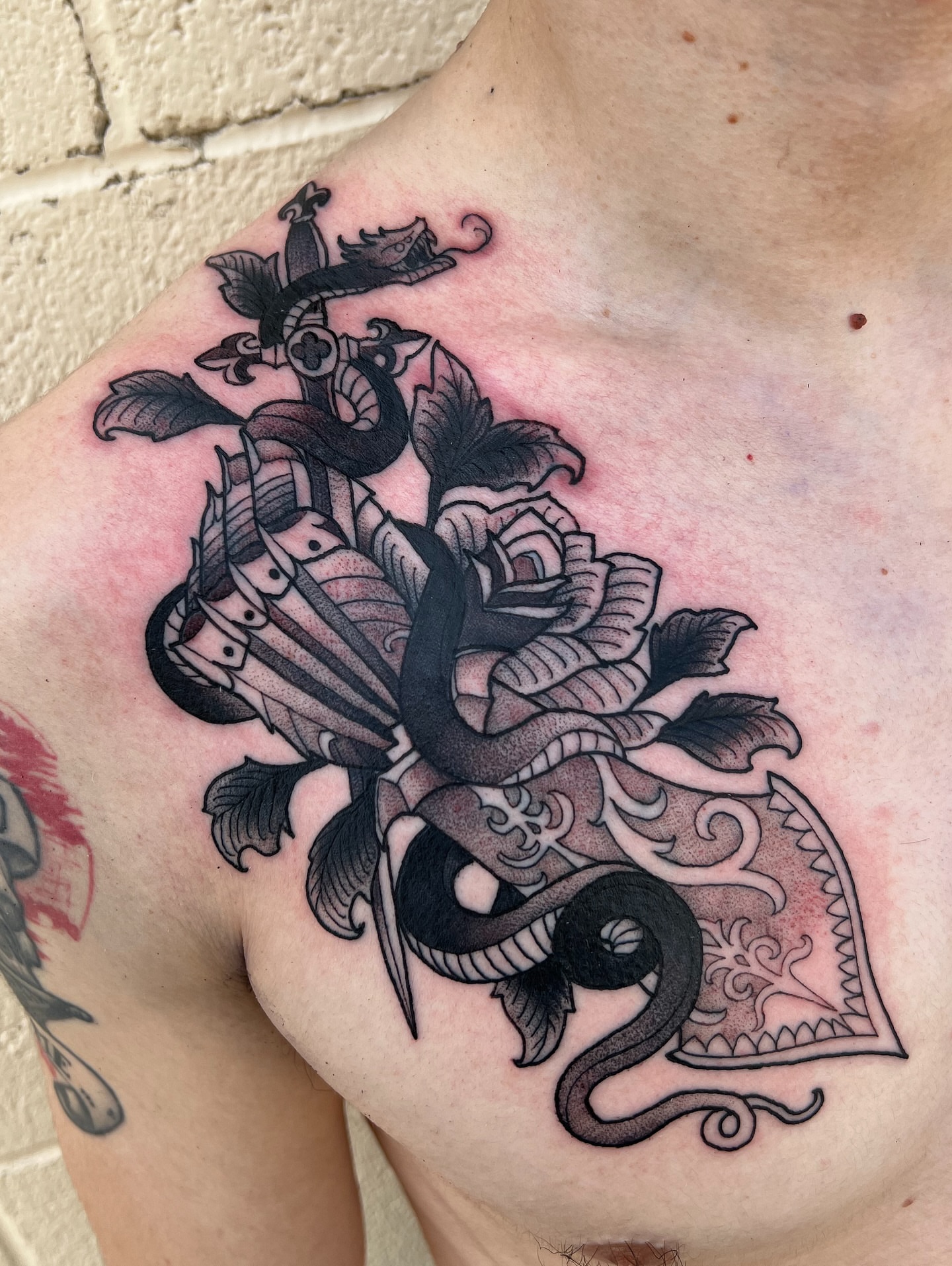 Snake and rose ornamental tattoo on the chest by Nathan Garcia