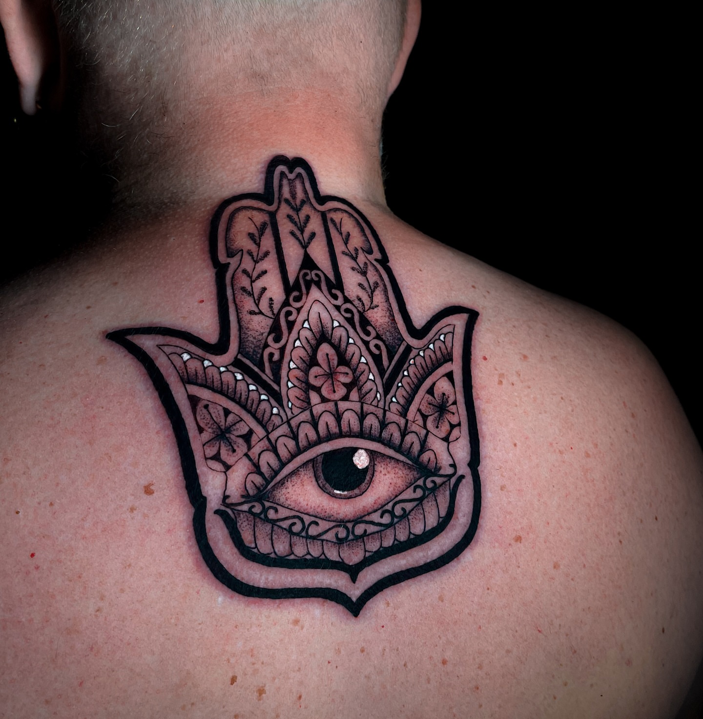 Eye and hamsa ornamental tattoo on the back by Miguel Henrik