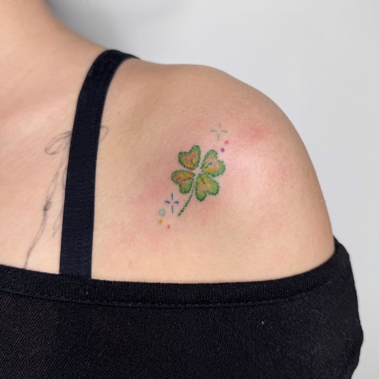 Four-leaf clover watercolor tattoo on the shoulder by Yez tattoo