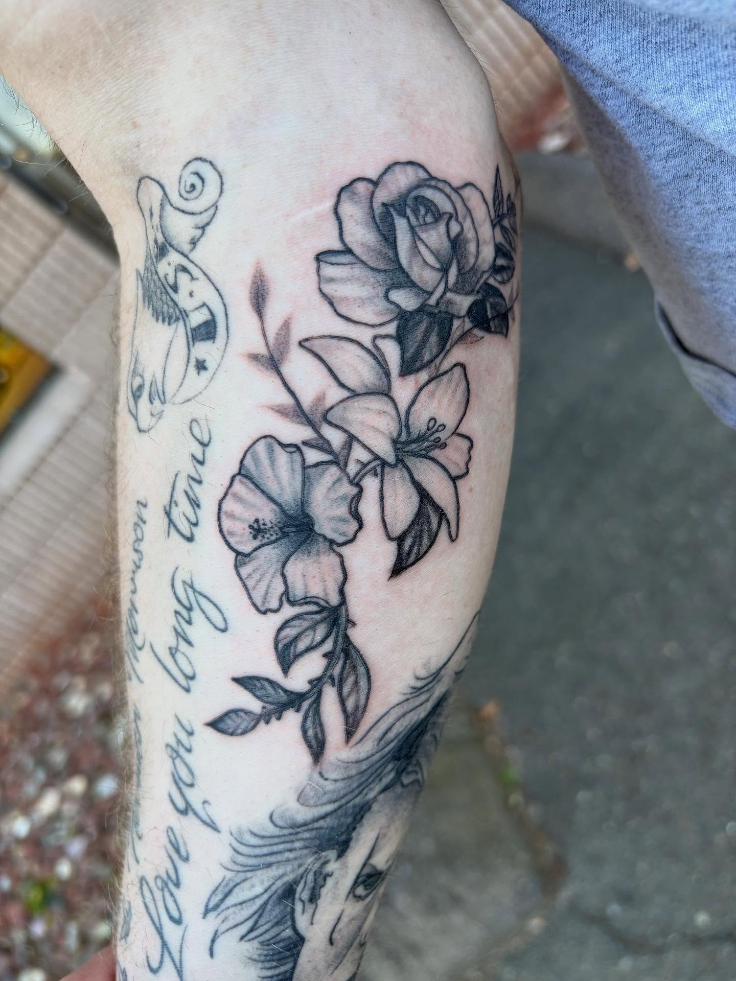 Floral arrangement black and grey tattoo on the forearm by Luke
