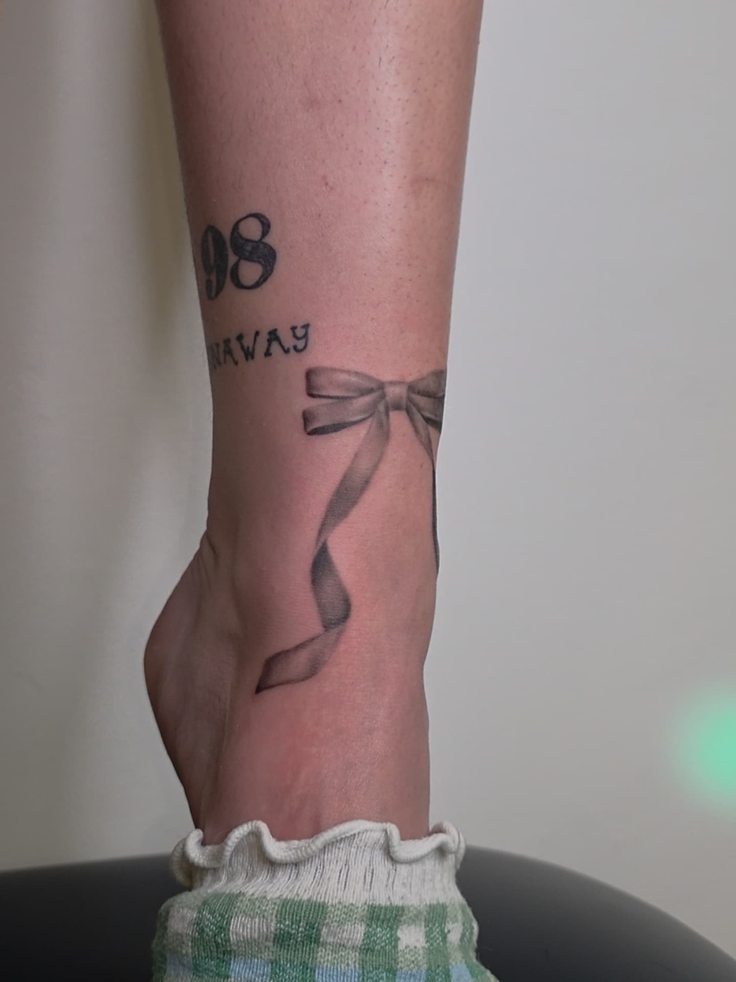Bow and ribbon black and grey tattoo on the forearm by Ashley Johnson, Knoxville, Tennessee