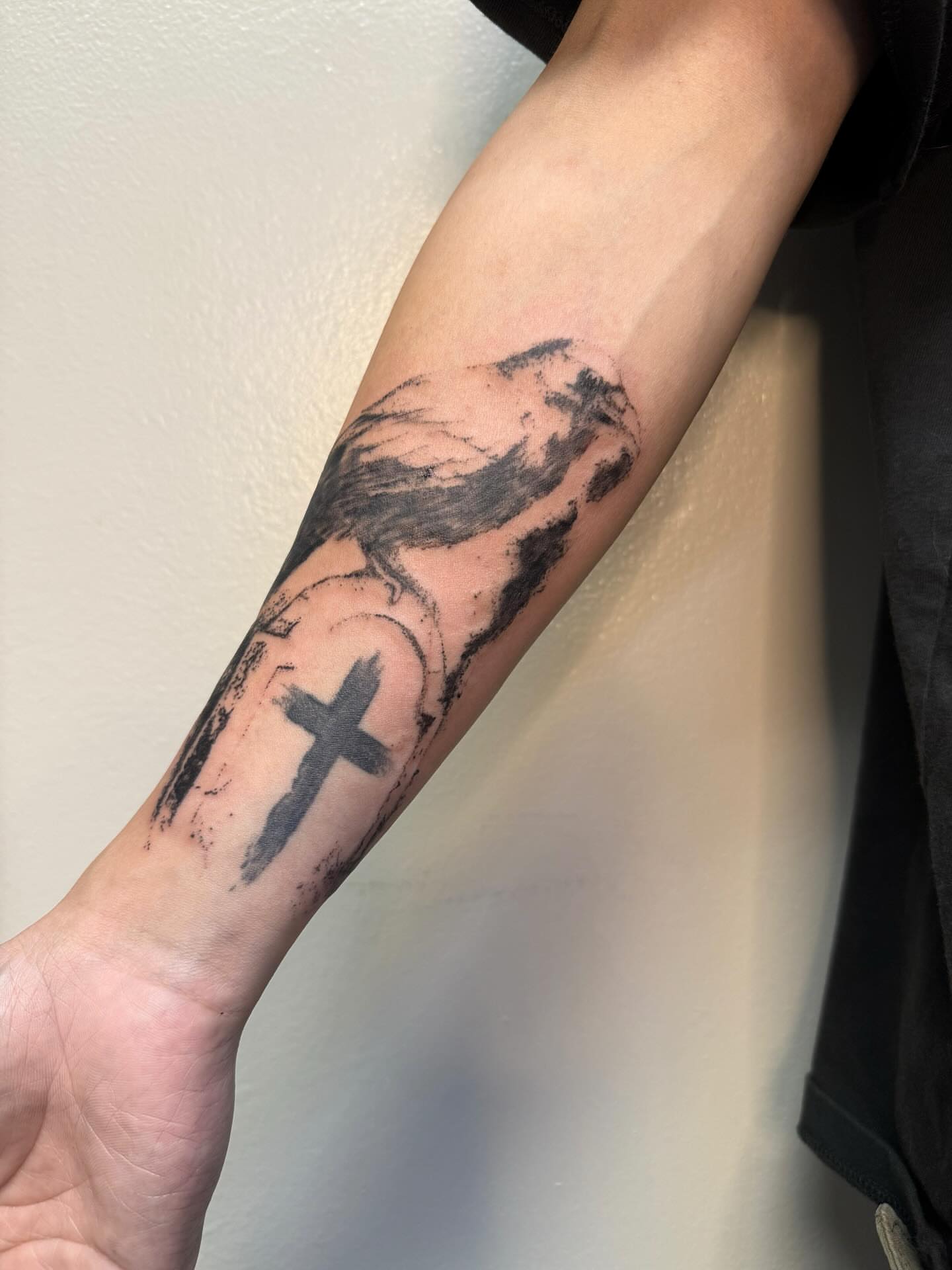 Cross and bird black and grey tattoo on the forearm by Joey tattoo