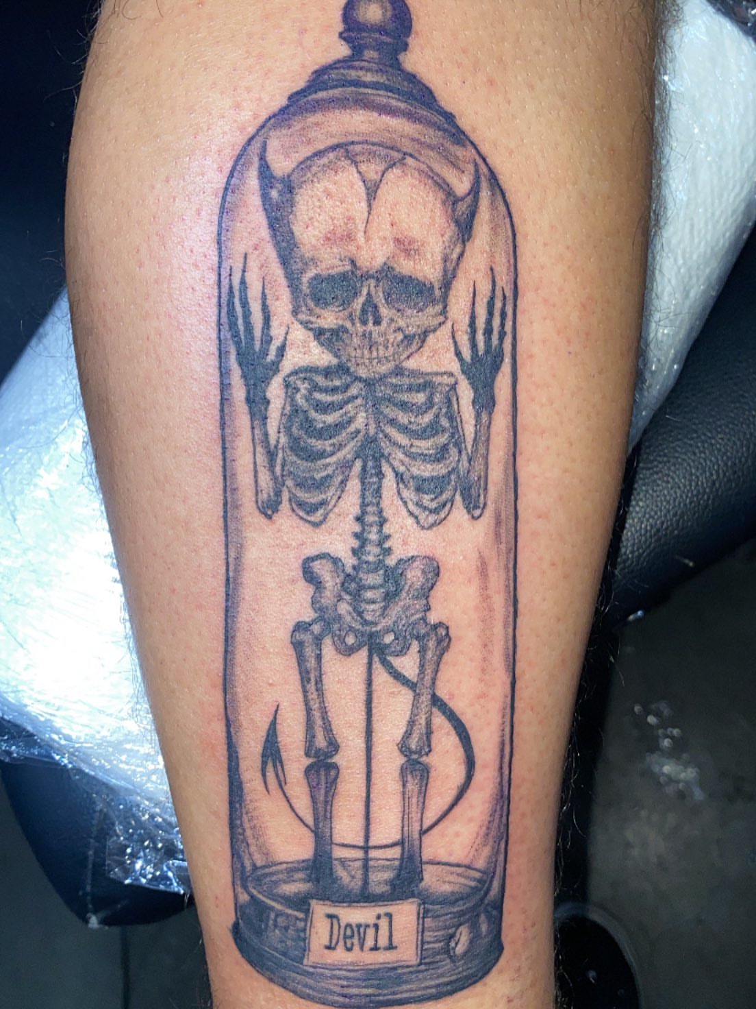 Skeleton in bell jar realism tattoo on the leg by Hecho En El Bronx