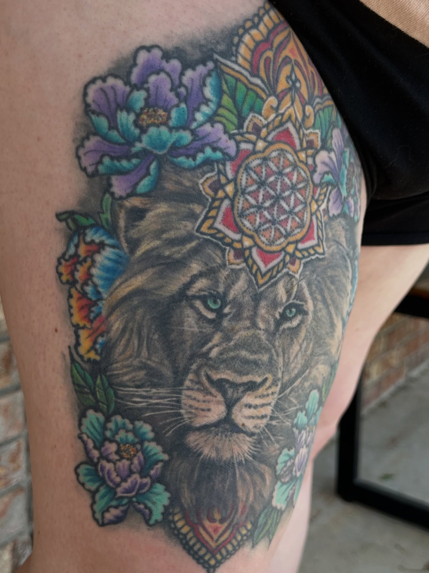 Lion with flowers and mandala tattoo on the thigh by Matthew Tattooer Harman