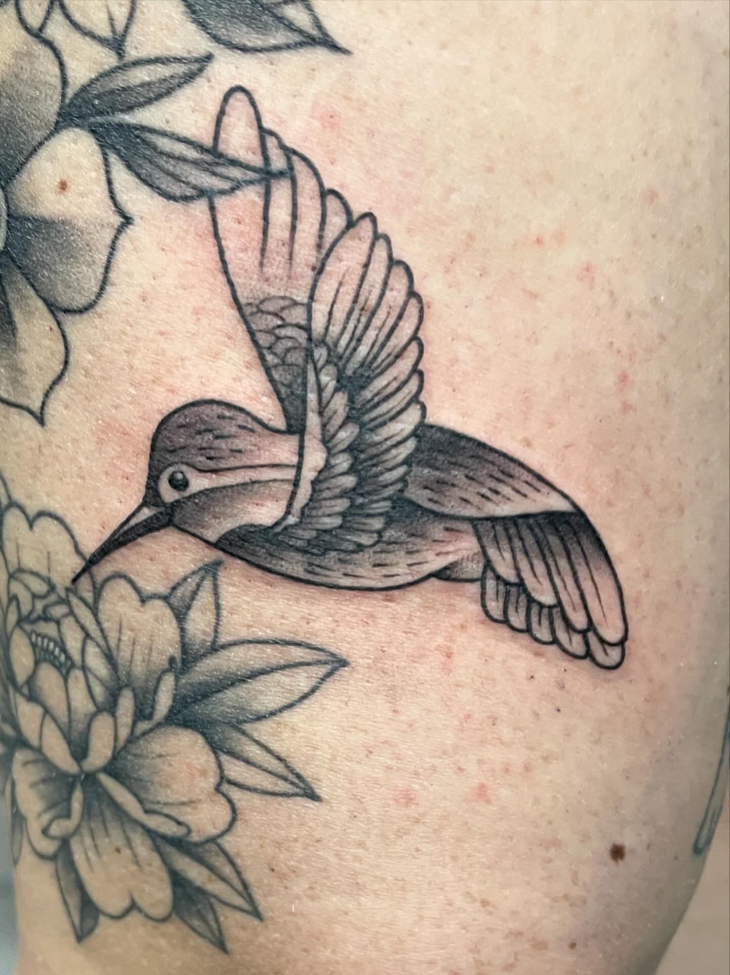 Hummingbird and flowers black and grey tattoo on the thigh by Natalie