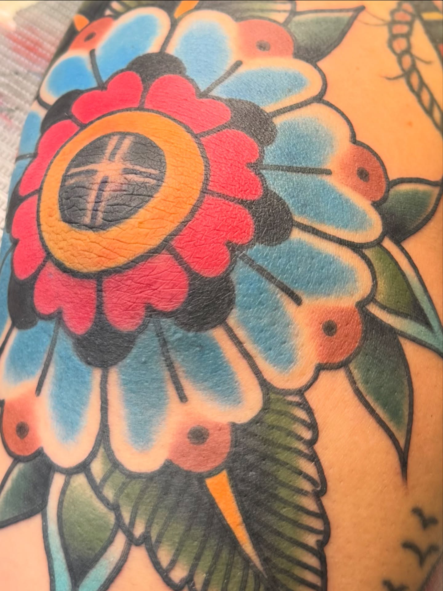 Flower American traditional tattoo on the upper arm by Jeremy Hudson