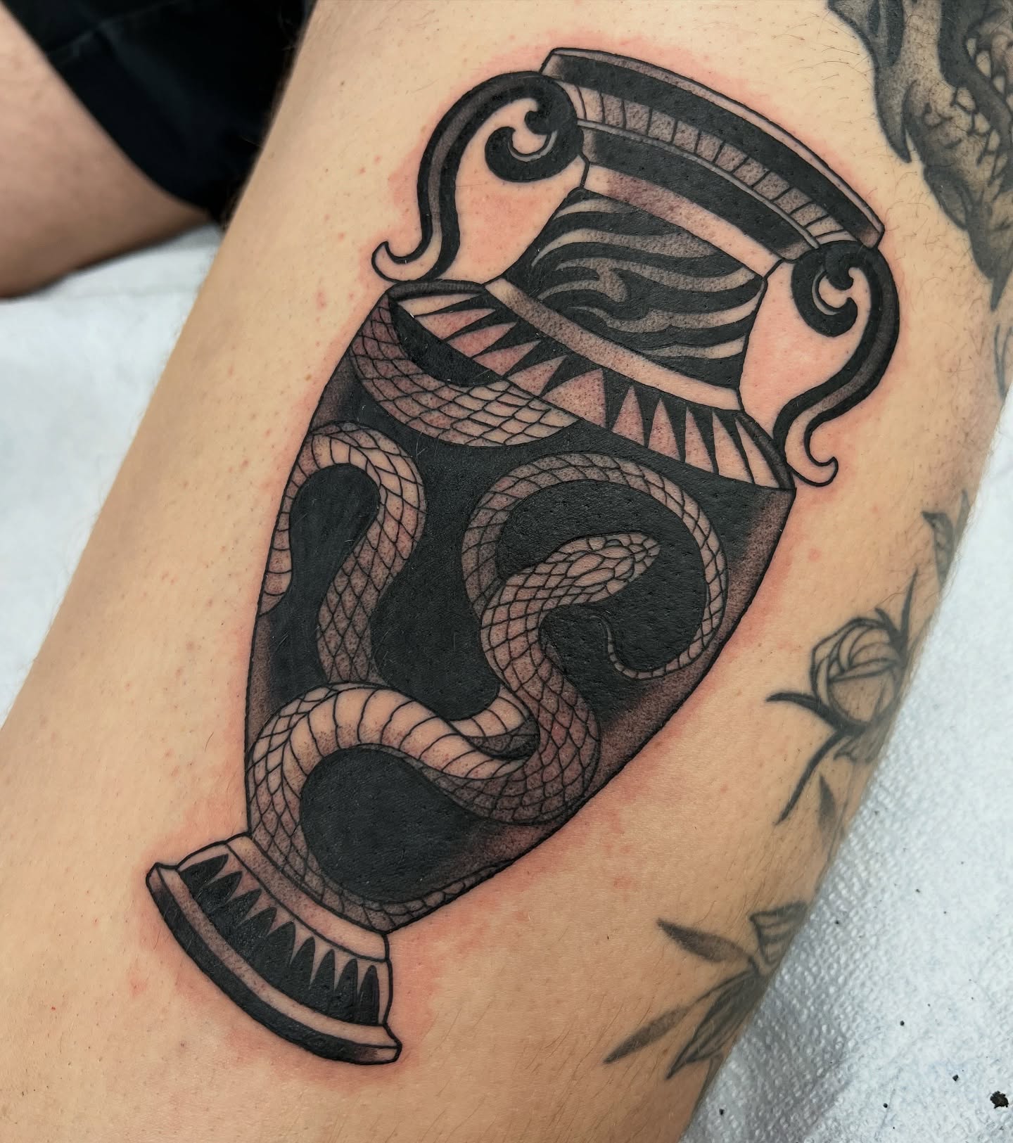 Serpent and shield black and grey tattoo on the thigh by Nathan Garcia