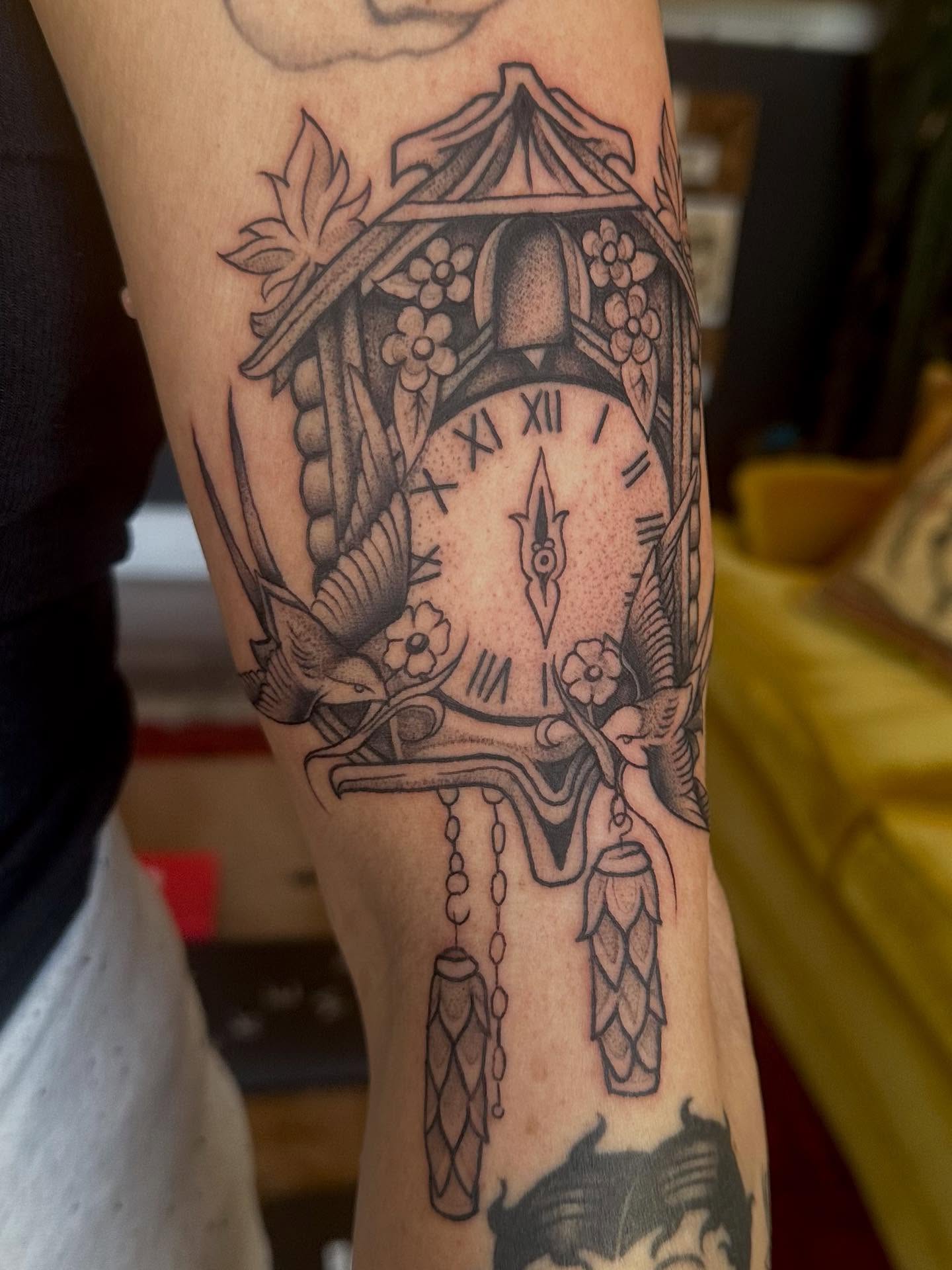 Clock with birdhouse black and grey tattoo on the forearm by Lia Massari