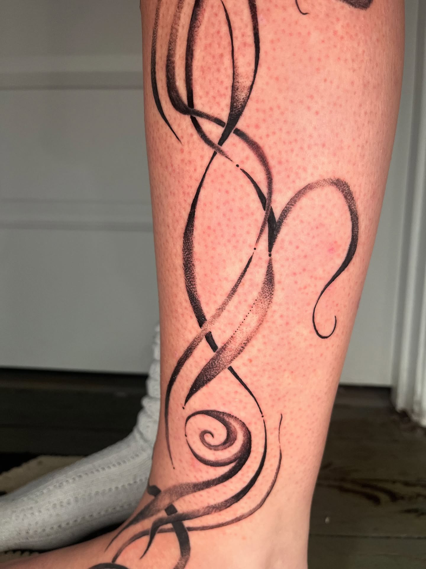 Abstract swirls dotwork tattoo on the calf by layne
