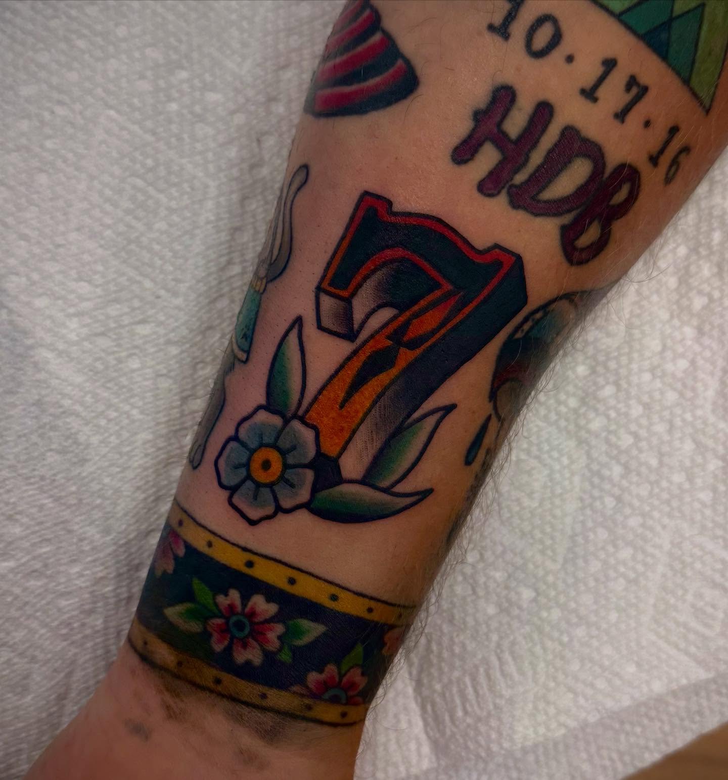 Number 7 with floral elements American traditional tattoo on the forearm by Sam Babcock