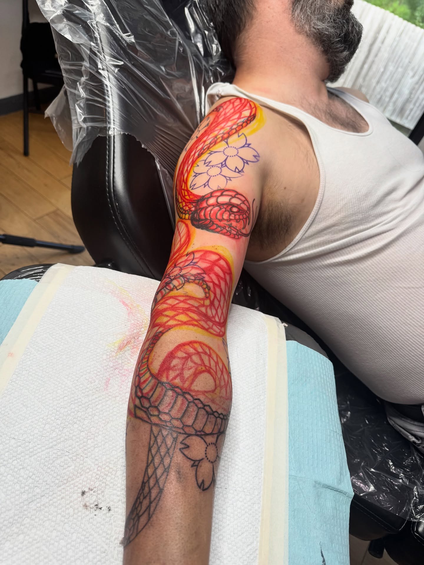 Snake and flowers American traditional tattoo on the upper arm by David Gray