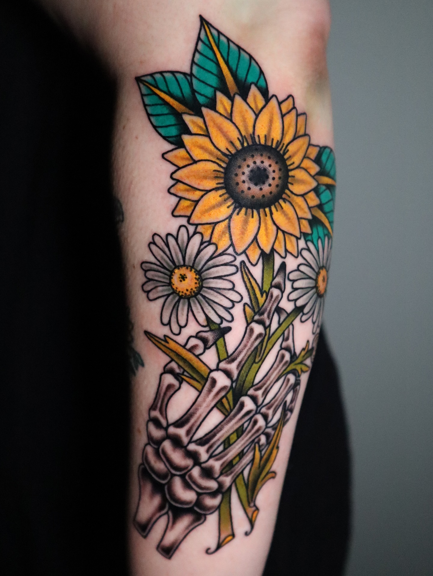 Sunflower and skeleton hand American traditional tattoo on the forearm by Lauren Howard Tattoos