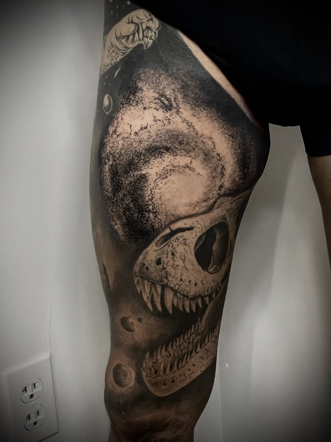 Dinosaur skull in space realism tattoo on the thigh by Charlie