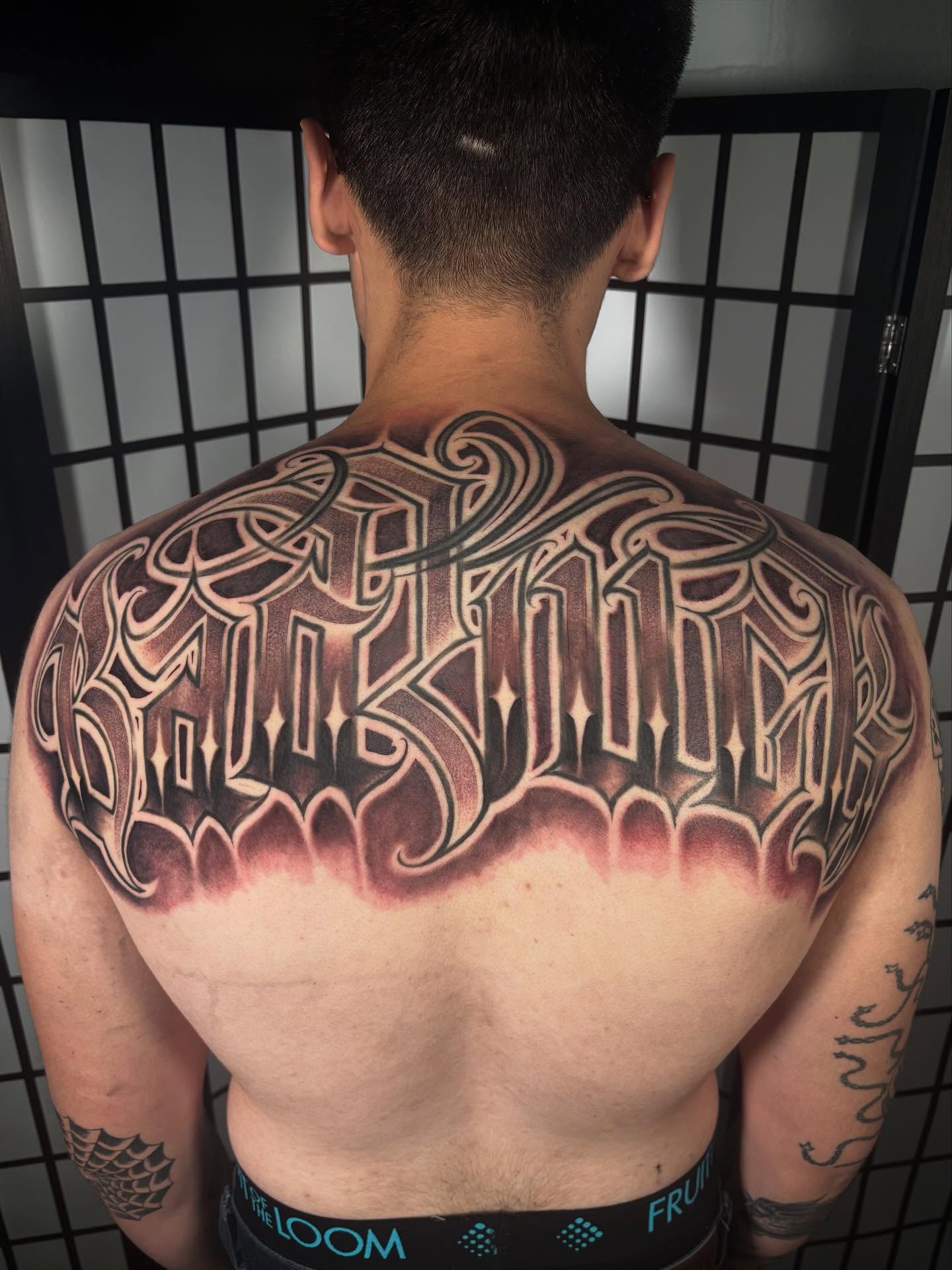 Gothic script tattoo on the back by Trusty Dizon Tattoo Artist