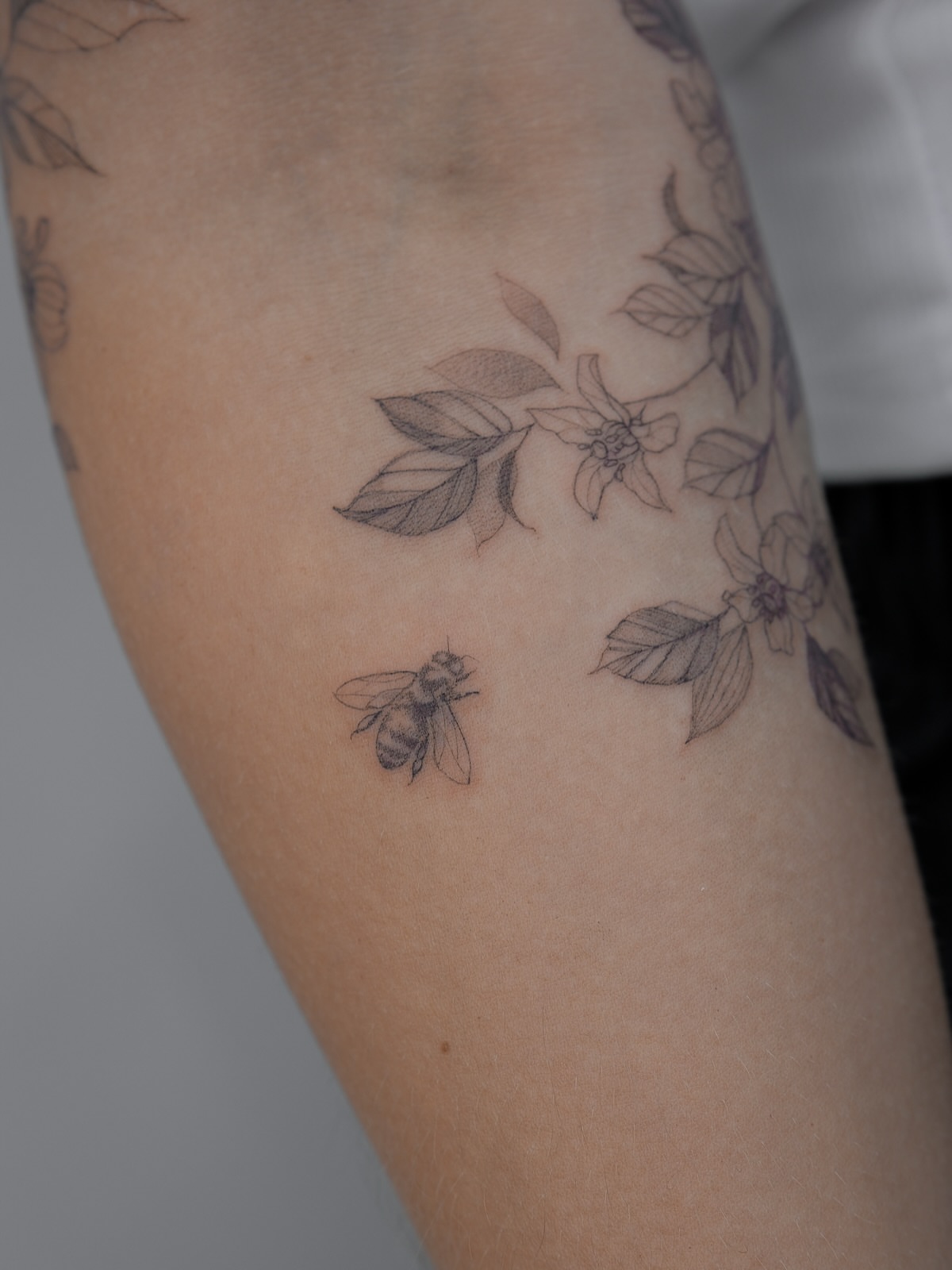 Bee and flowers black and grey tattoo on the forearm by Tattoo in Charlotte NC, Charlotte, North Carolina