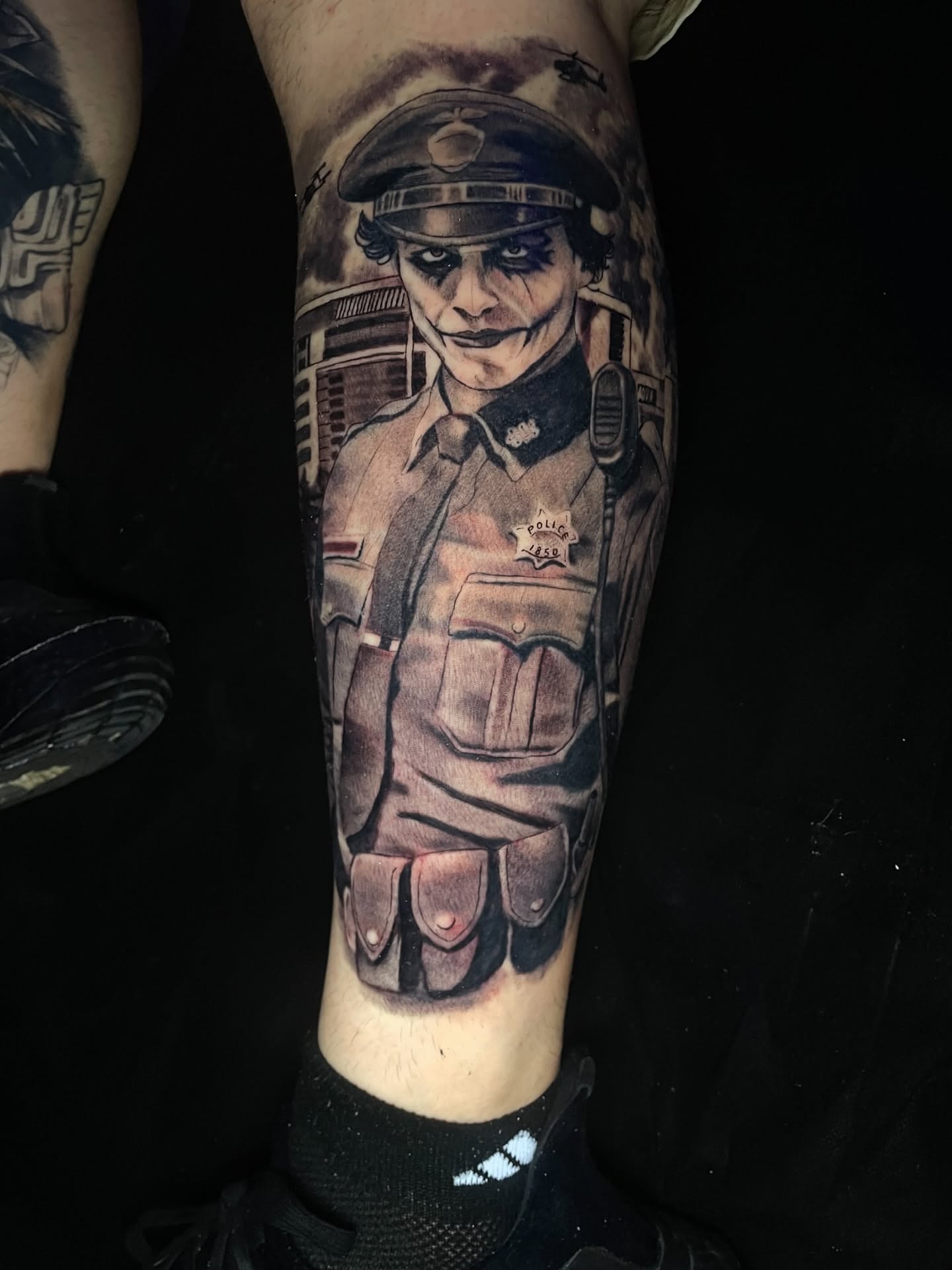 Joker police officer dark realism tattoo on the forearm by Vic