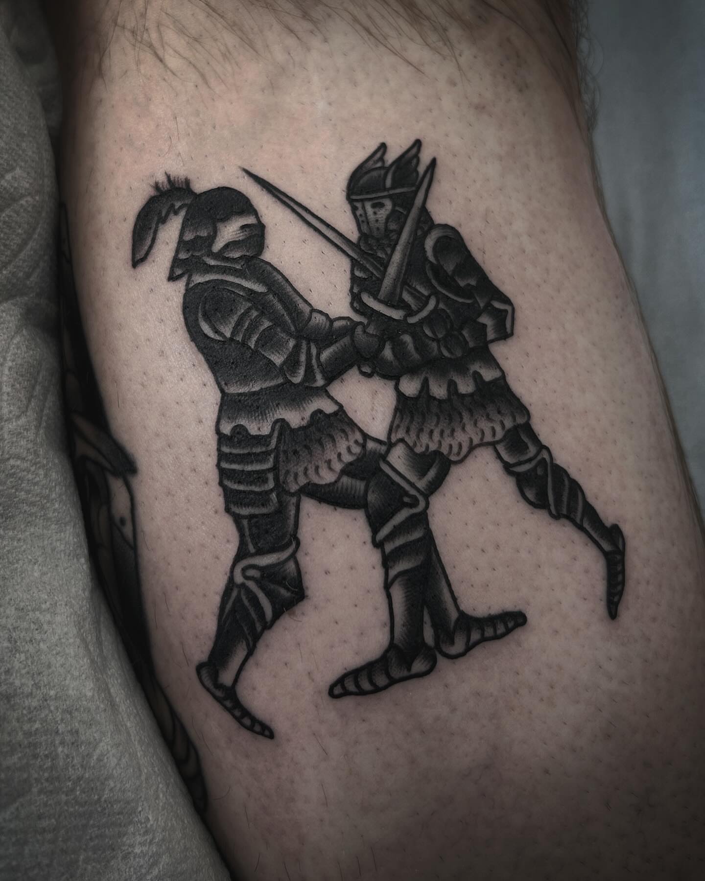 Dueling knights black and grey tattoo on the thigh by Samantha C, Bremerton, Washington