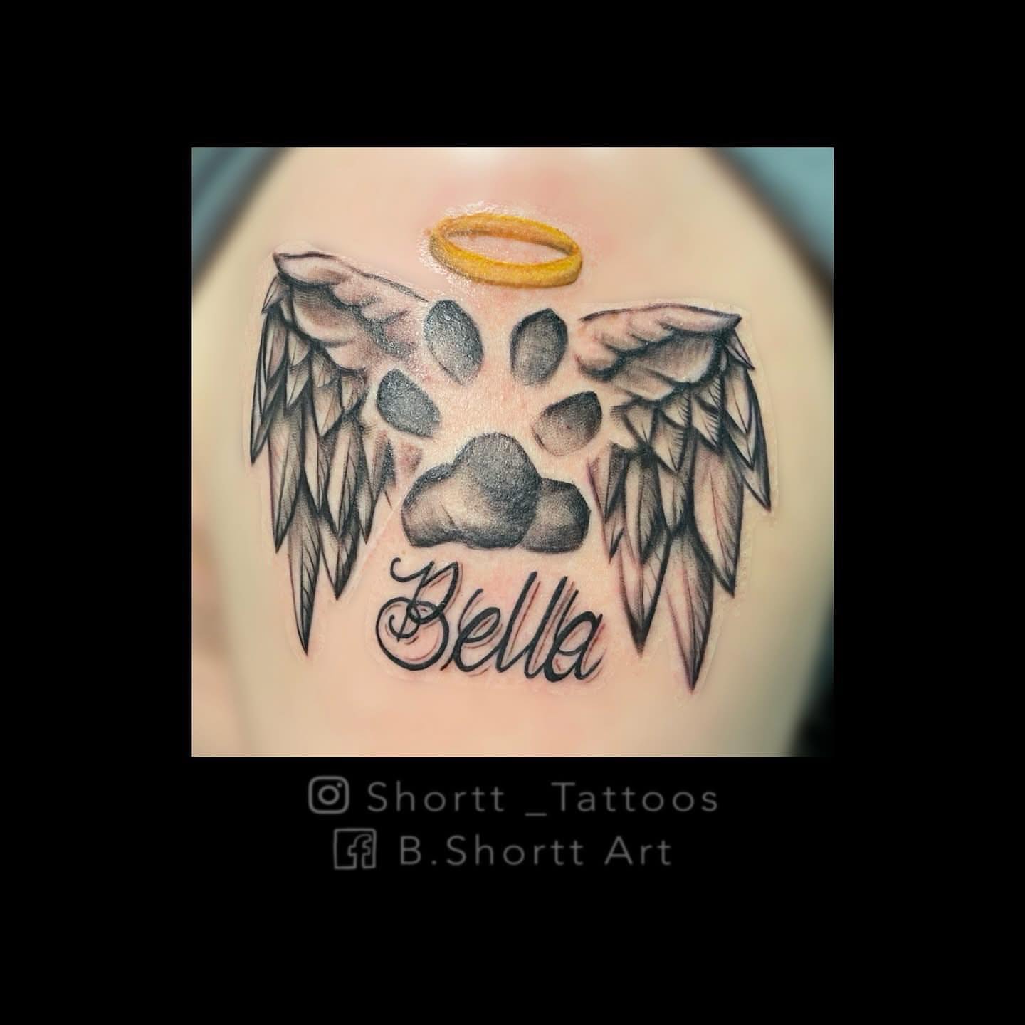Angel wings and paw print black and grey tattoo on the shoulder by Brie Marie