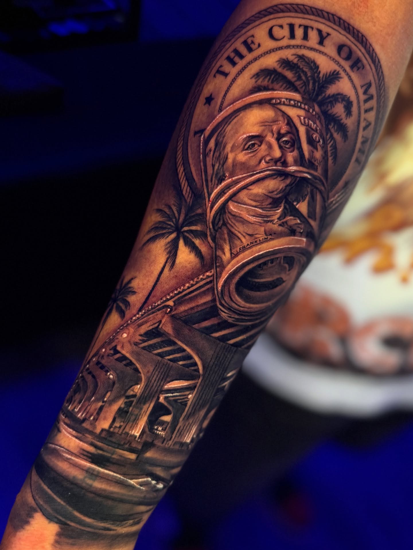 Dollar bill and bridge realism tattoo on the forearm by Raw Hound, Hialeah, Florida